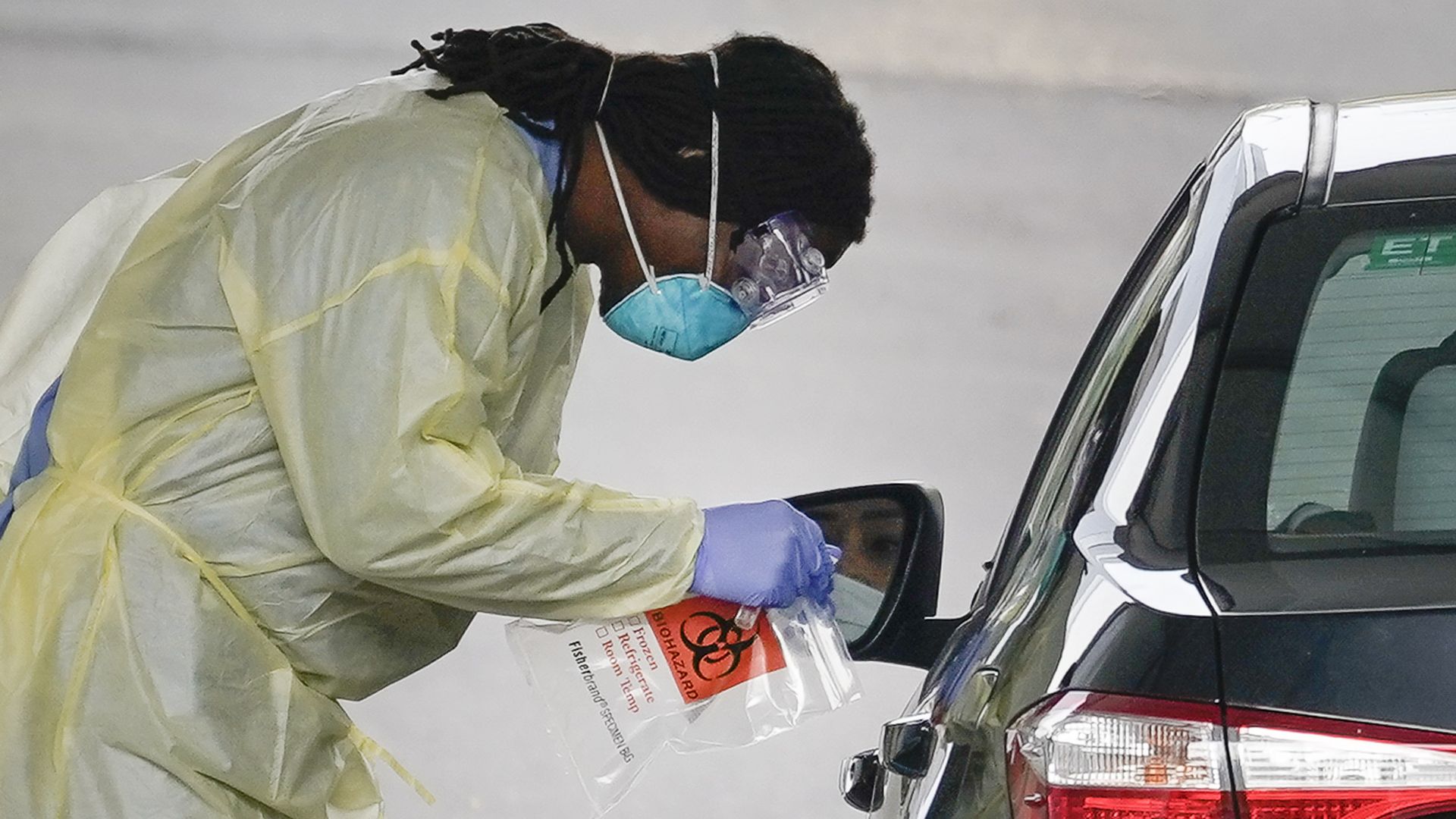 A photo of a a healthcare worker screening a patient for COVID-19 at a drive-through coronavirus testing site on March 18, 2020 in Arlington, Virginia.