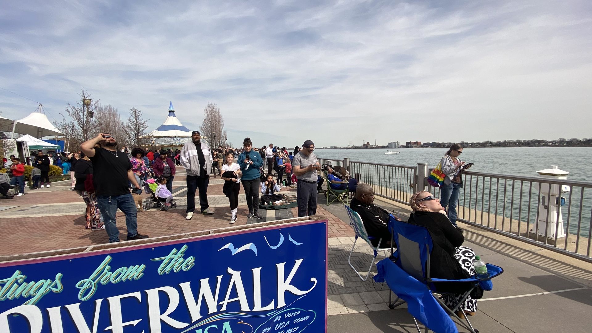 People look up at the sun on the riverfront during the eclipse.