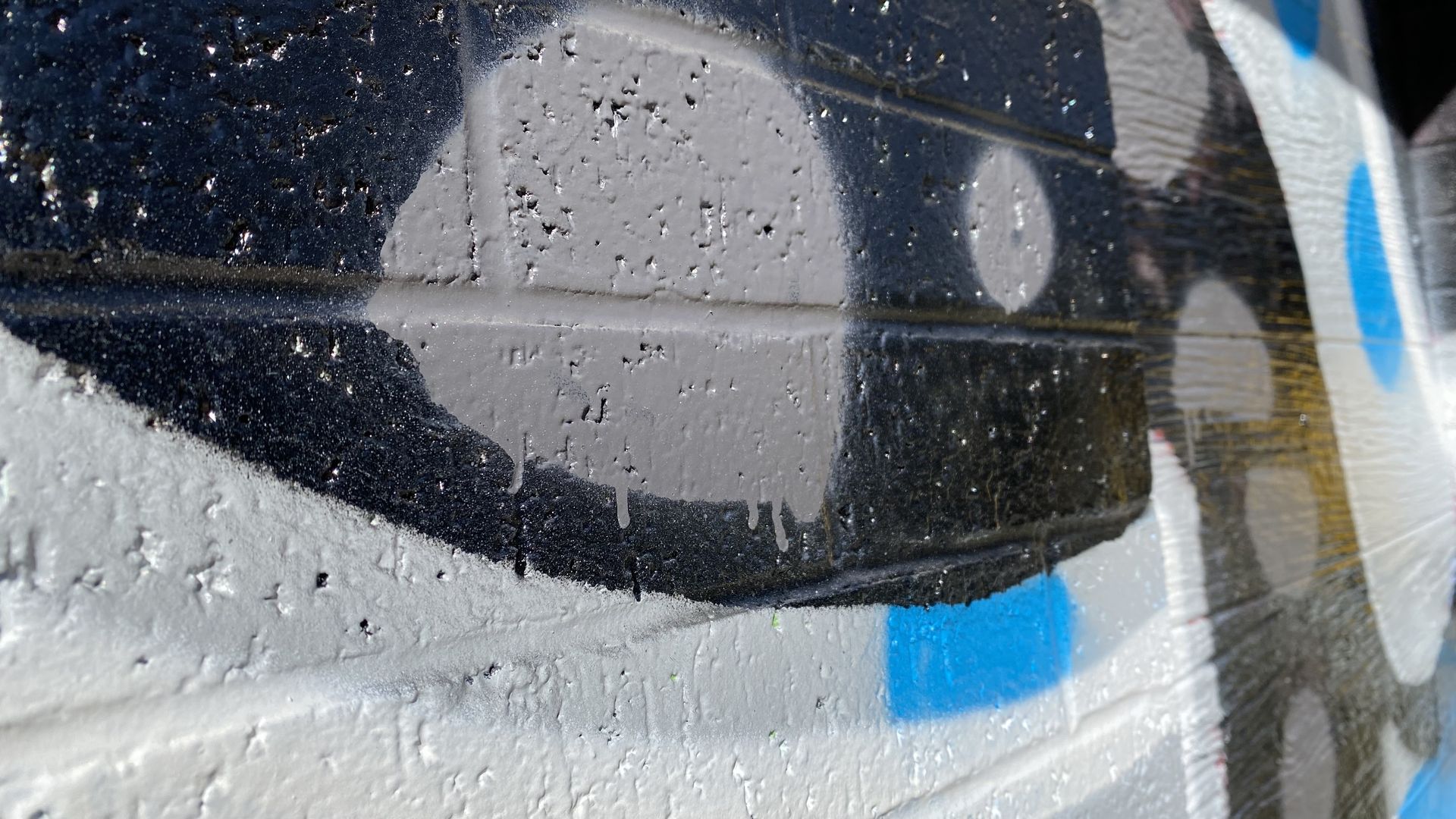 A close-up image of a brick wall that's been spray painted in graffiti with black, blue and gray paint.