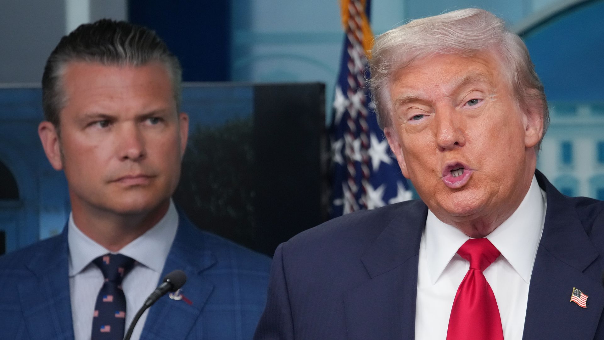 President Trump speaks at a White House podium with Defense Secretary Pete Hegseth standing nearby.