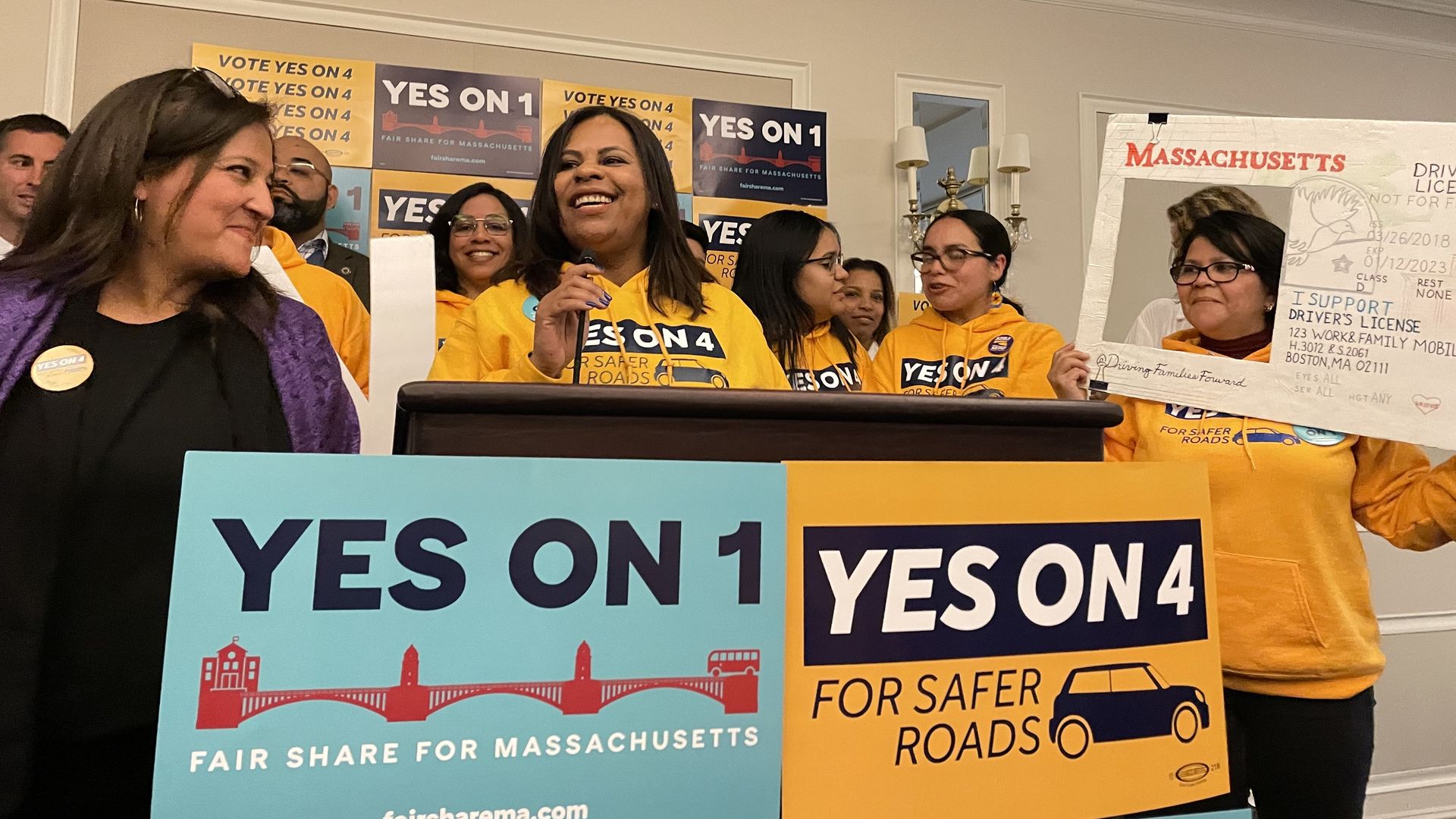 Lenita Reason of the Brazilian Worker Center speaks on the podium wearing yellow "Yes on 4" shirts at an election night party.