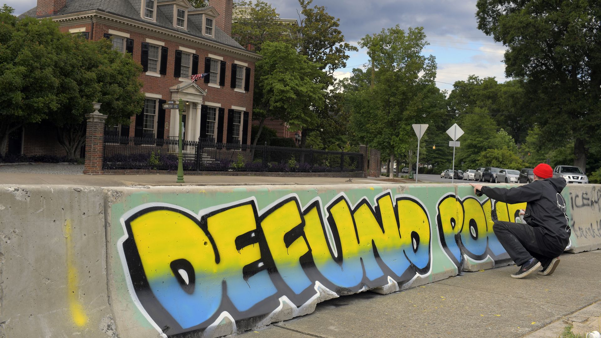 A street artist painting a "defund police" piece