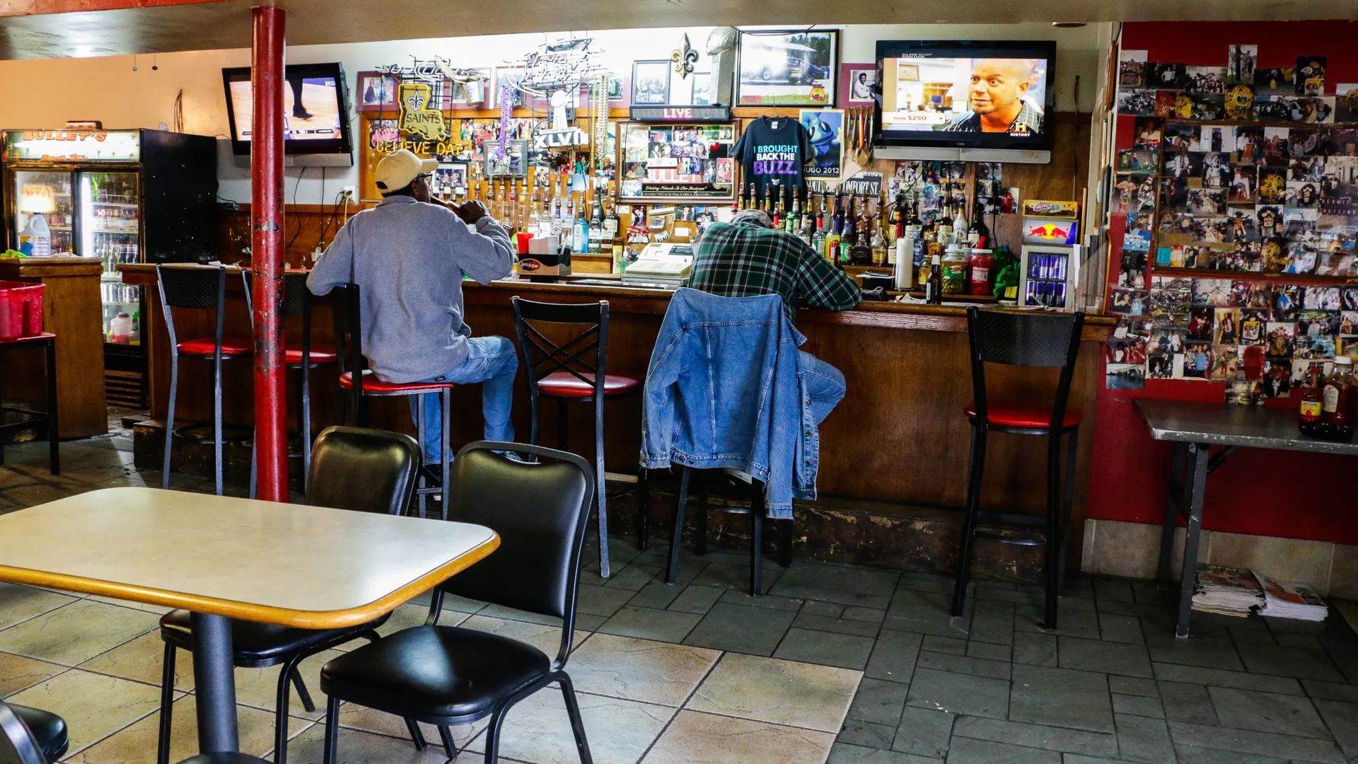 Two men are seen from behind as they sit at a bar.