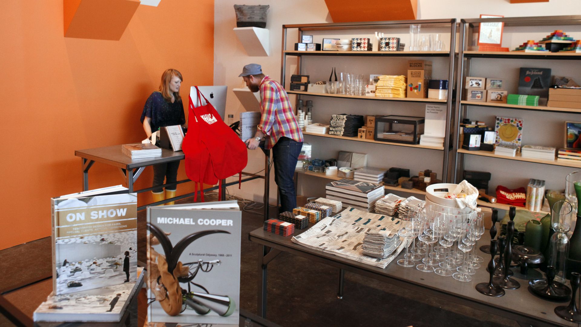 Photo of two people in a store filled with sculptures, glasses and books