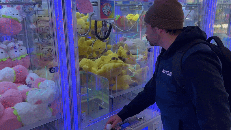A gif that shows Joe grabbing a sun shaped stuffed animal from a claw machine 