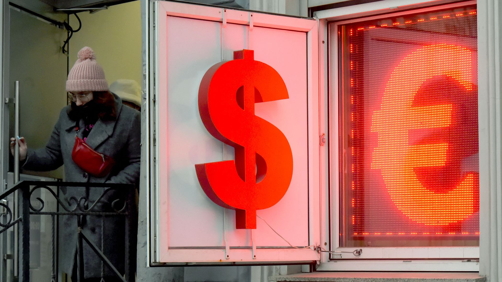 A woman leaves a currency exchange office displaying the US dollar and the euro signs in Saint Petersburg on March, 2, 2022. 