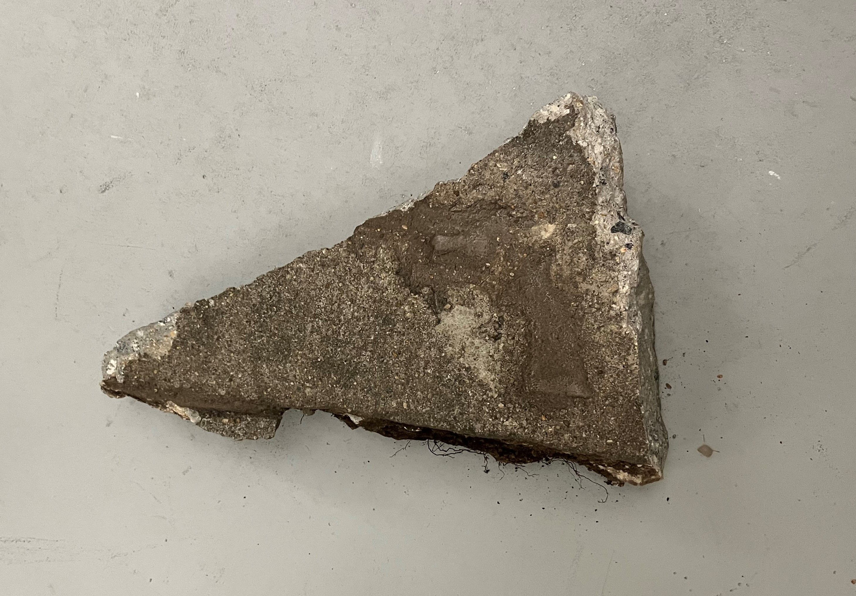 a chunk of sidewalk with an impression of a gun in it 