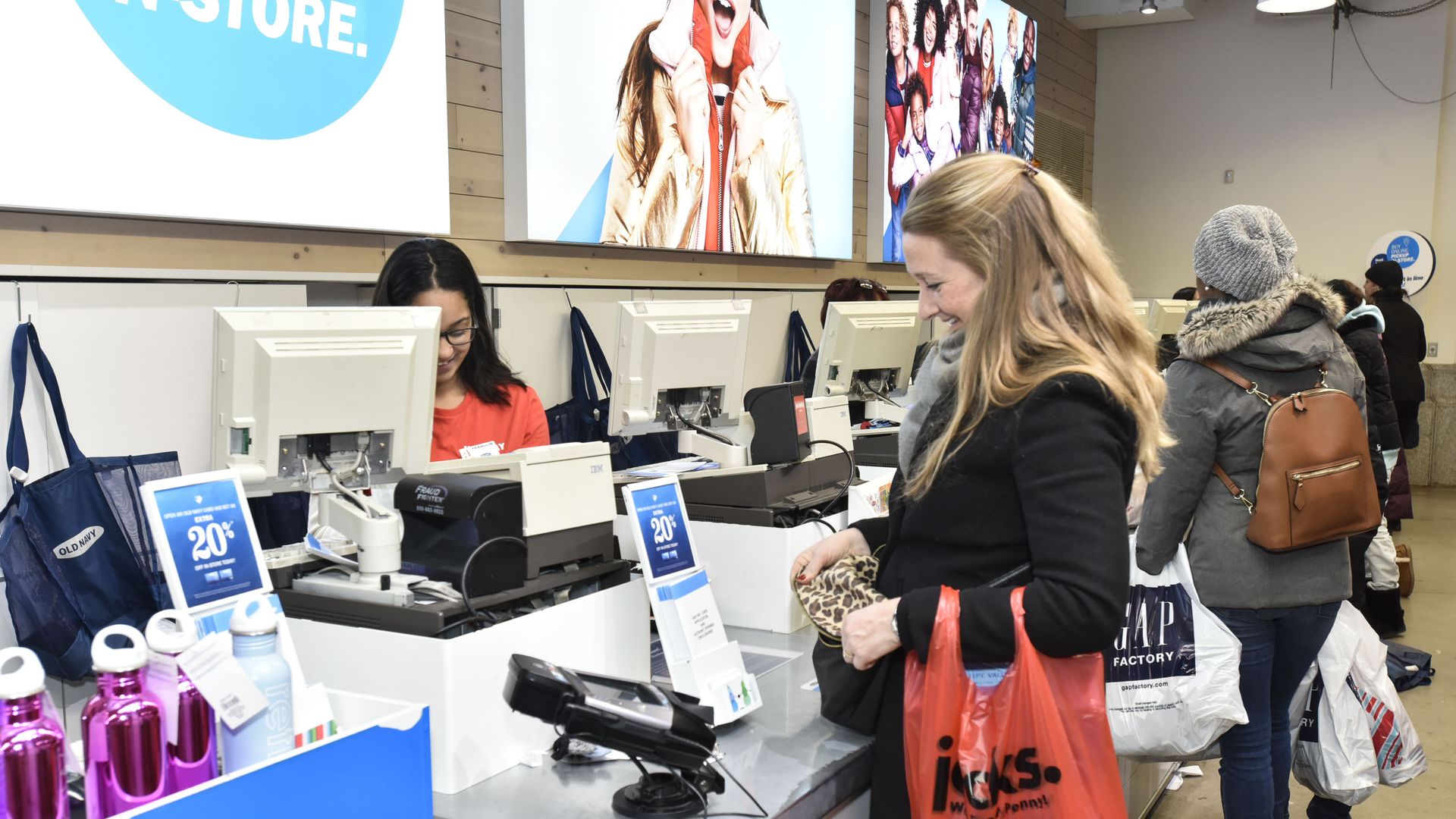 In this image, a woman in a winter coat pays for her items at Old Navy. 