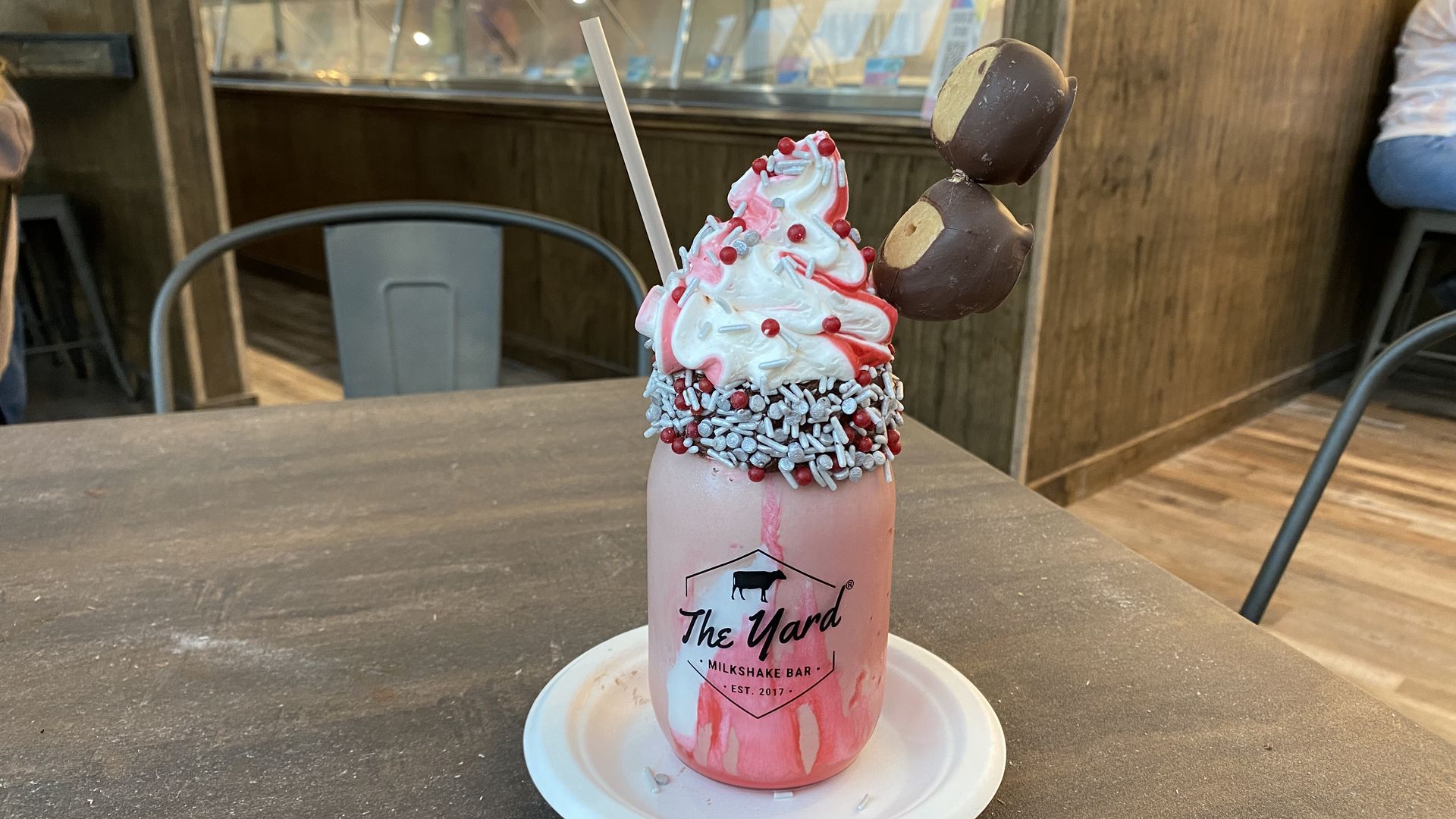 A red milkshake topped with whipped cream and buckeye candies on a stick