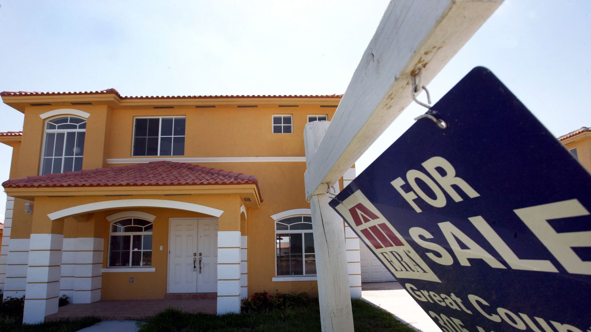 A house with a for-sale sign in the foreground
