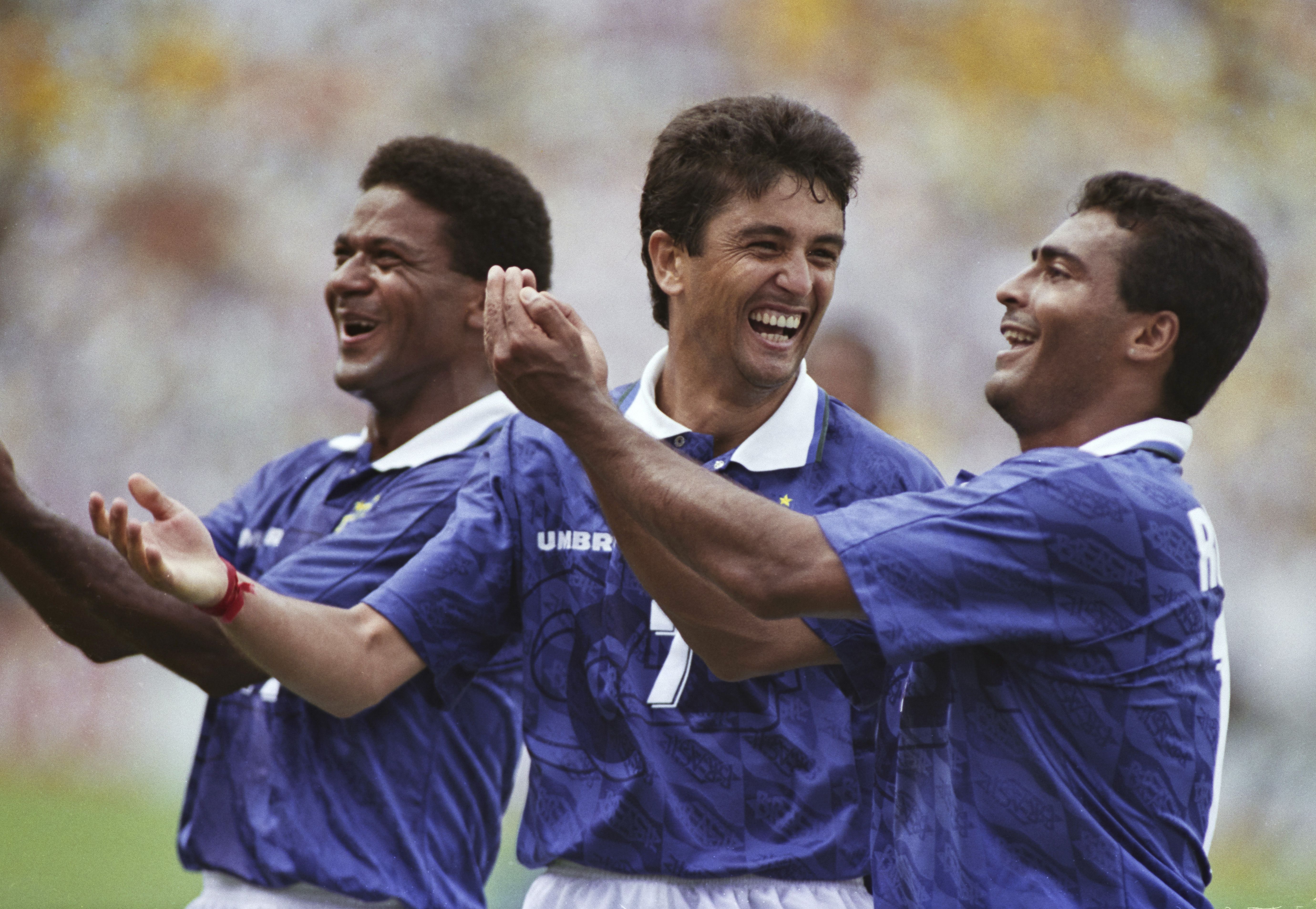 Three soccer players dressed in blue celebrate a goal.