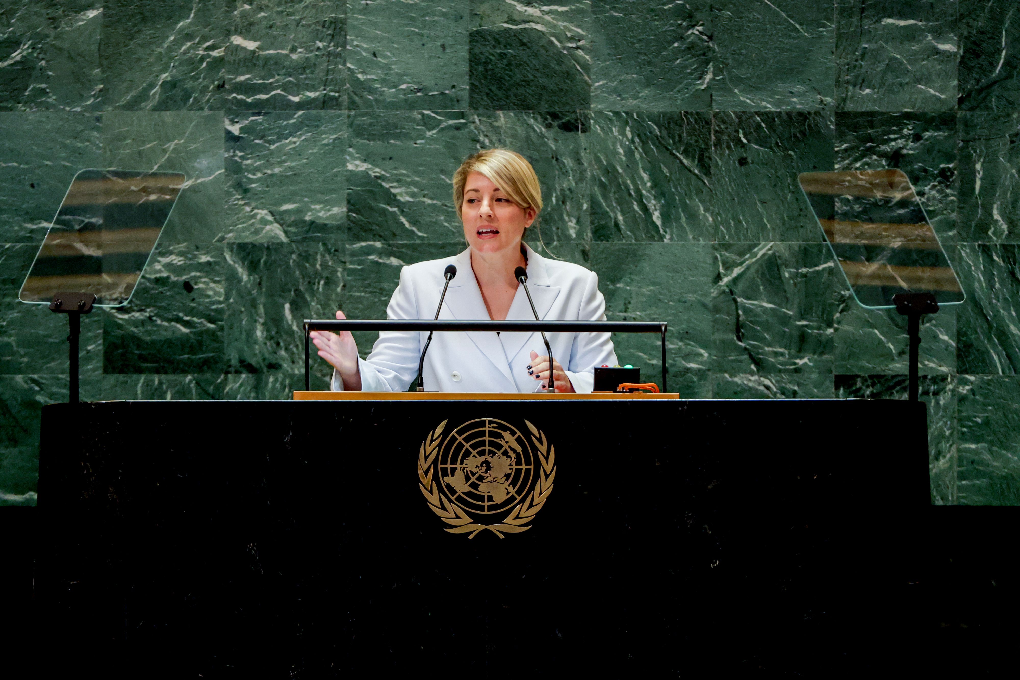 Melanie Joly speaks at a table wearing a white blazer