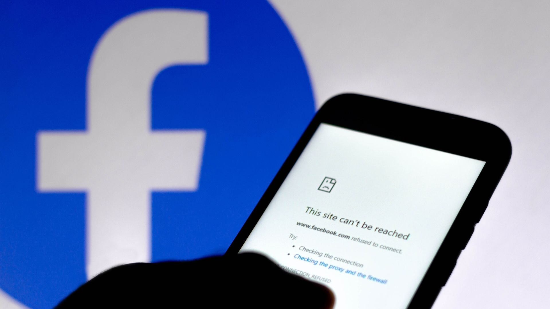  In this photo illustration, a message that says This site can't be reached, about an error of internet connection is seen on a smartphone screen with a Facebook logo in the background. 