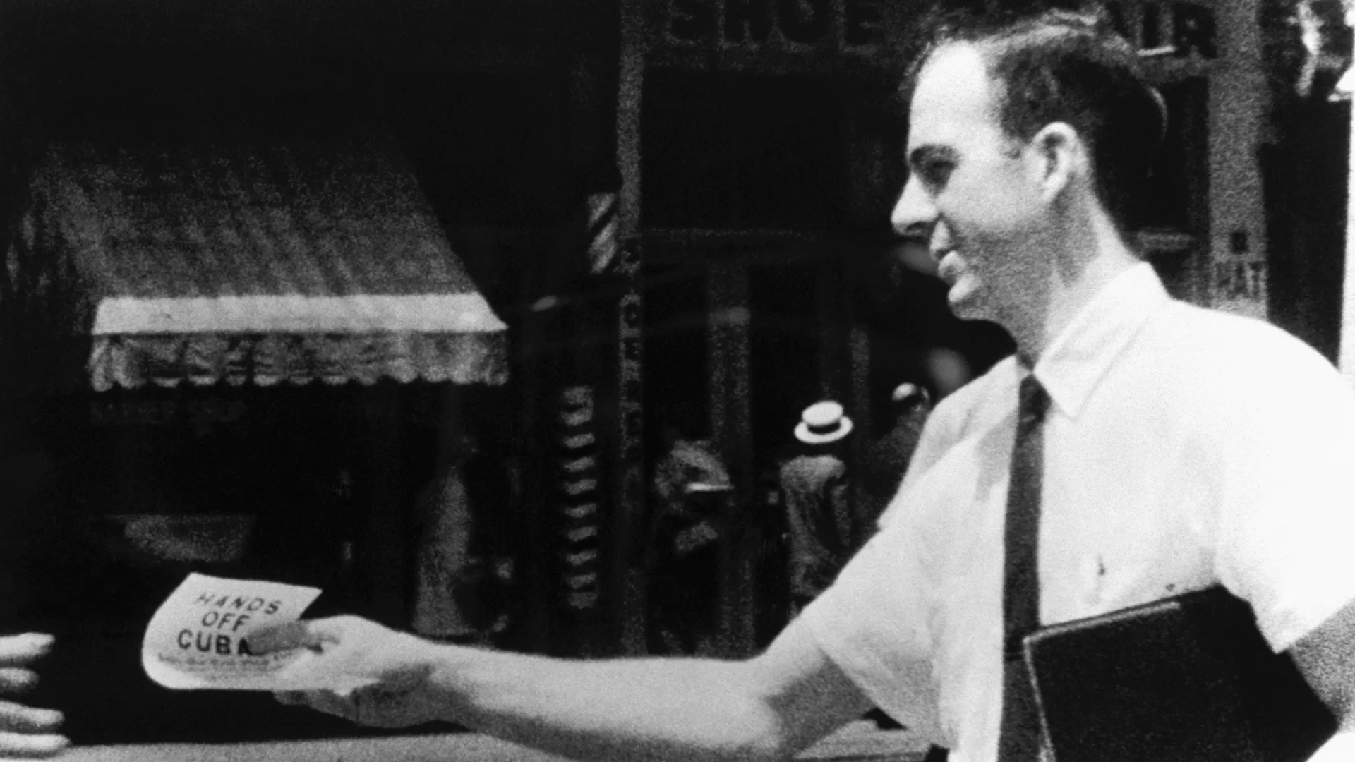Black and white photo of a man handing out a flyer that says "Hands off Cuba"