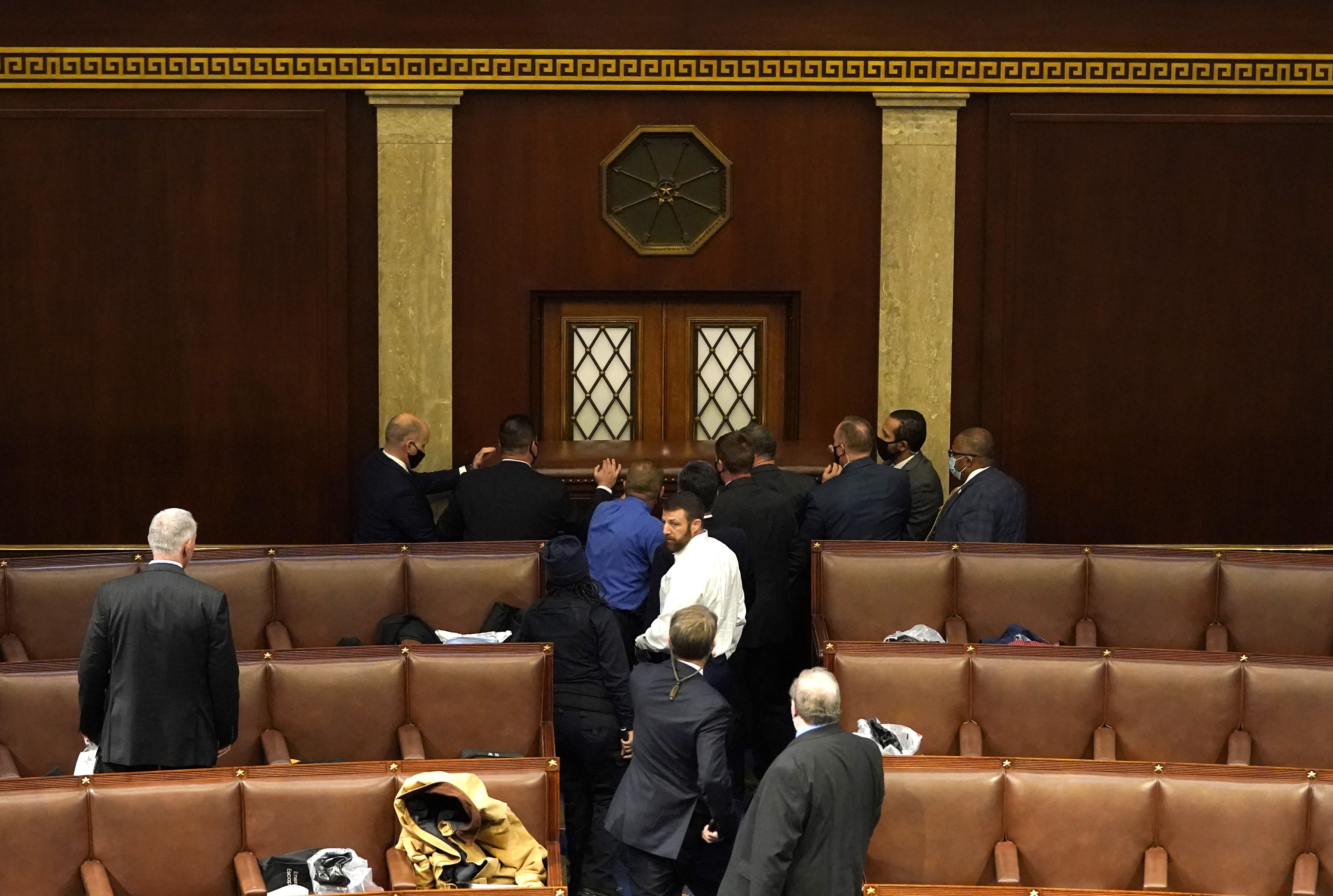 Picture of people in the House chamber blocking a door with a desk
