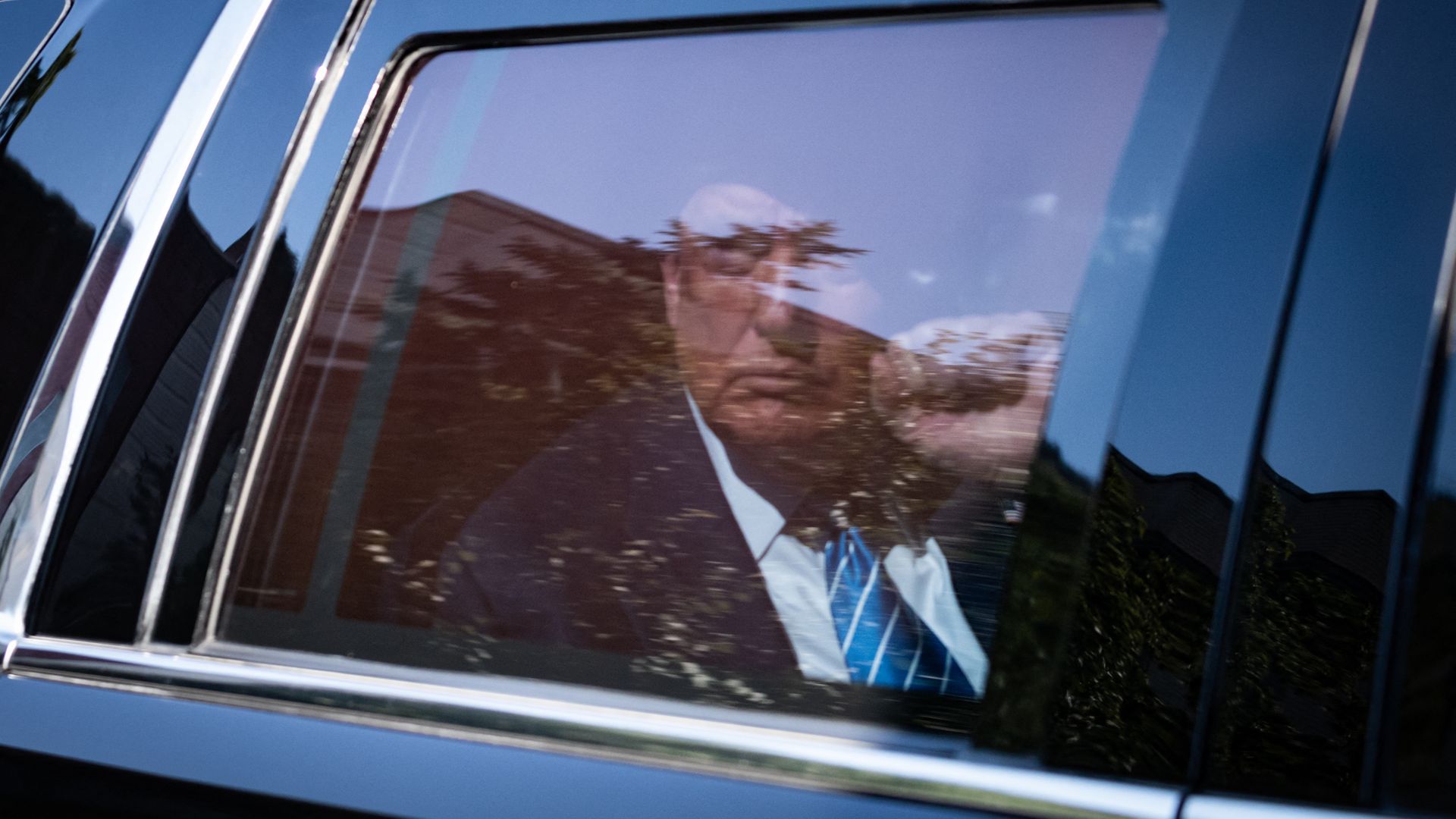 Former President Trump raising a fist behind a car window.