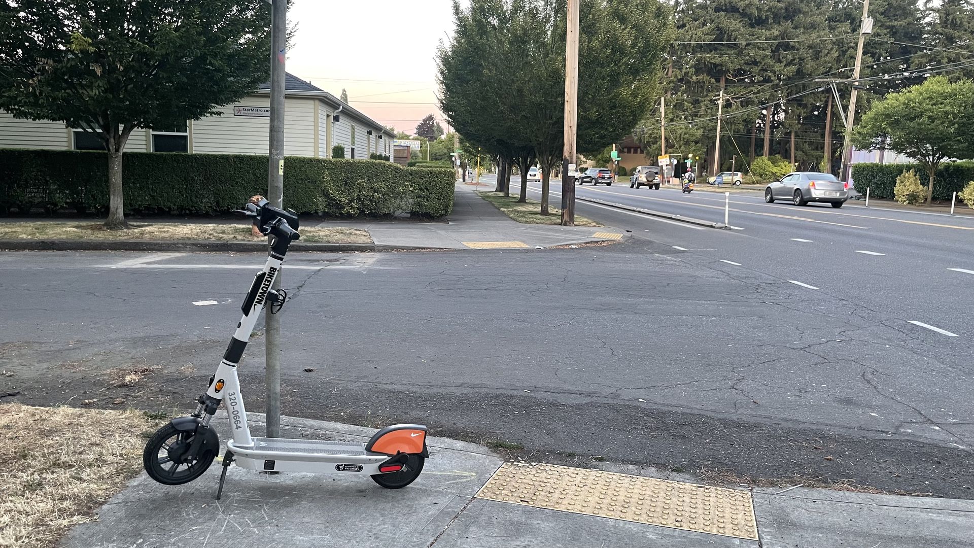 A photo of an electric scooter secured to a stop sign on the sidewalk.