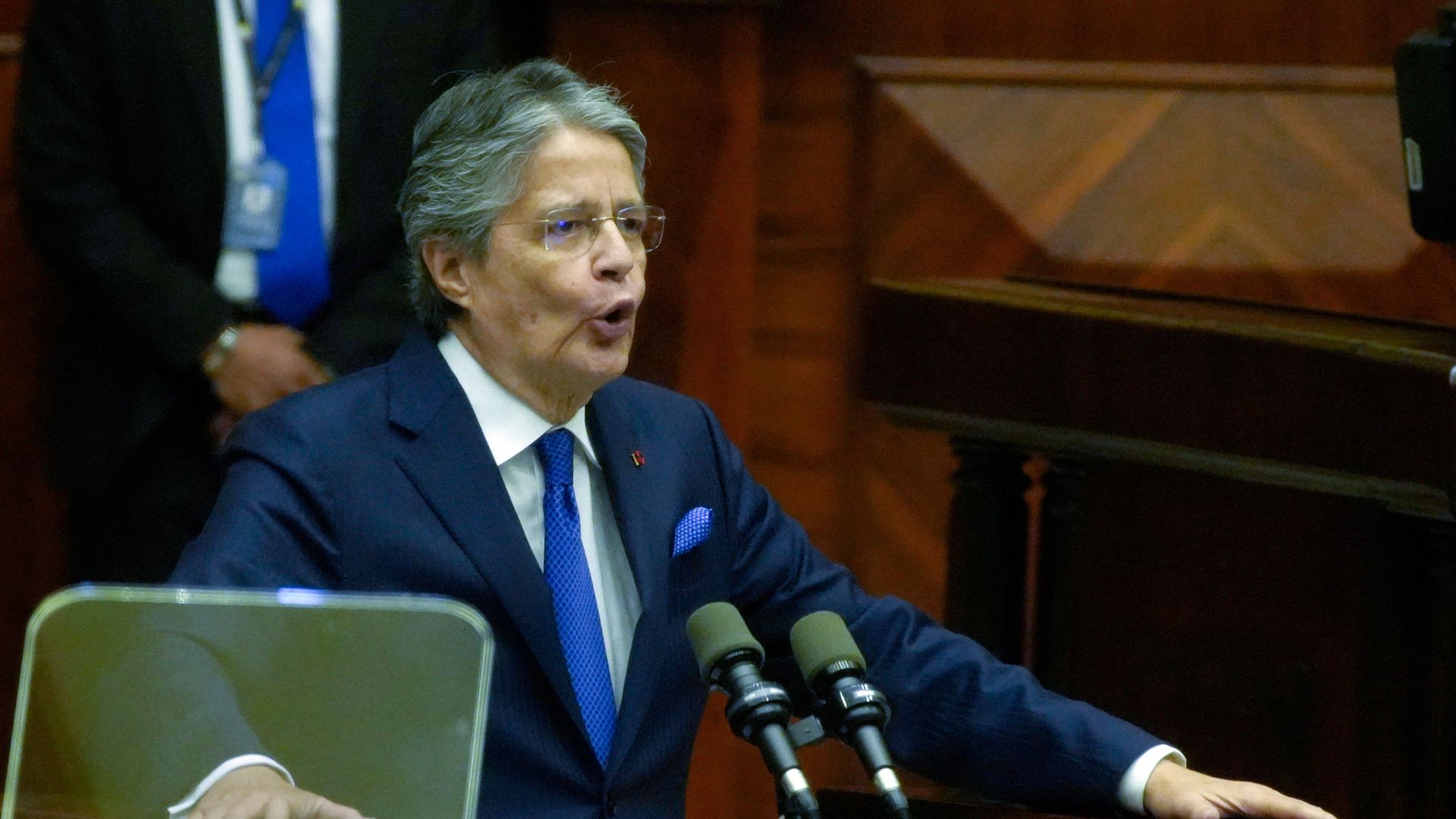 Ecuadorian president Guillermo Lasso speaks in front of two microphones during an impeachment hearing against him
