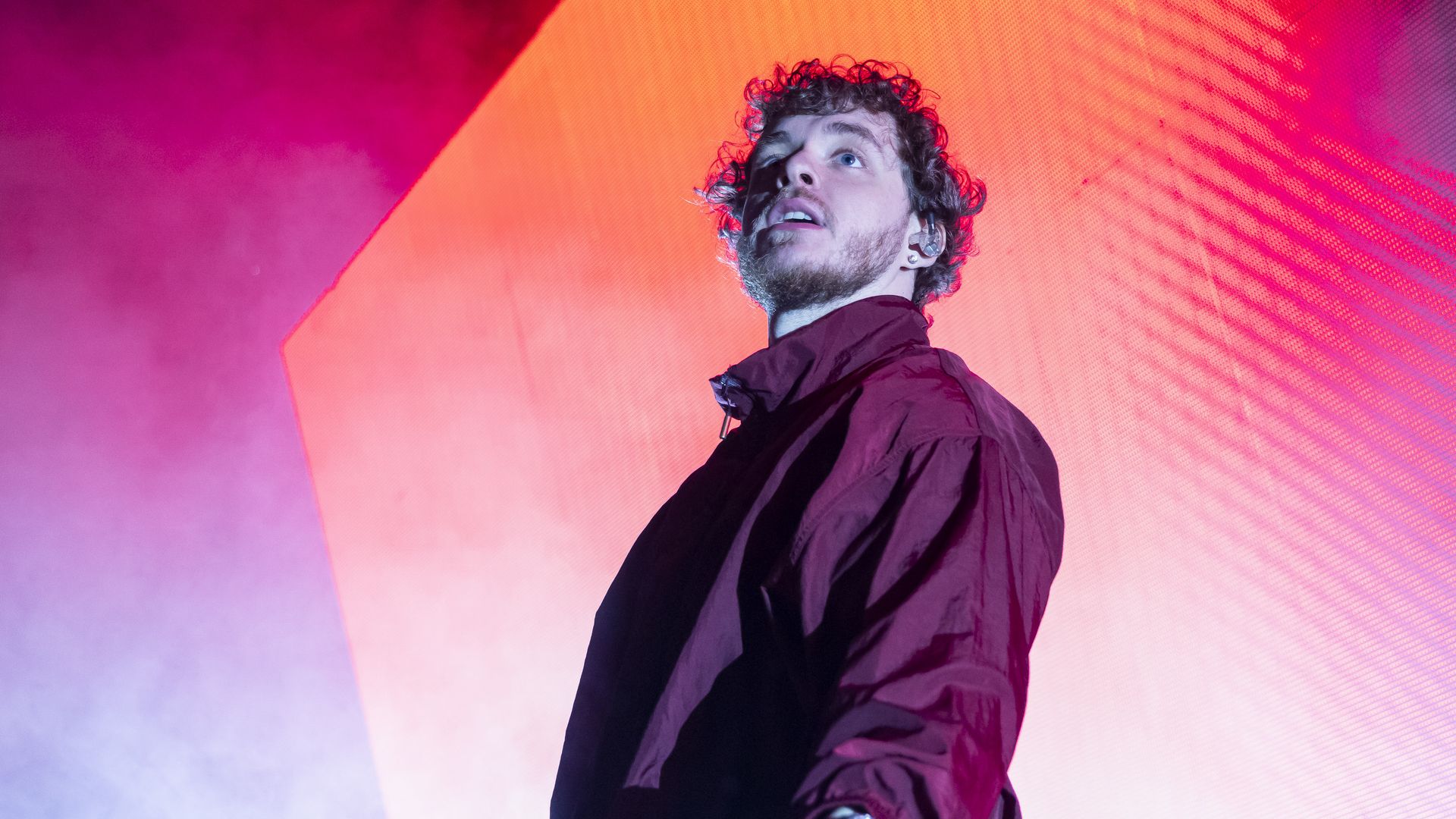 Jack Harlow wears a maroon tracksuit on stage. 