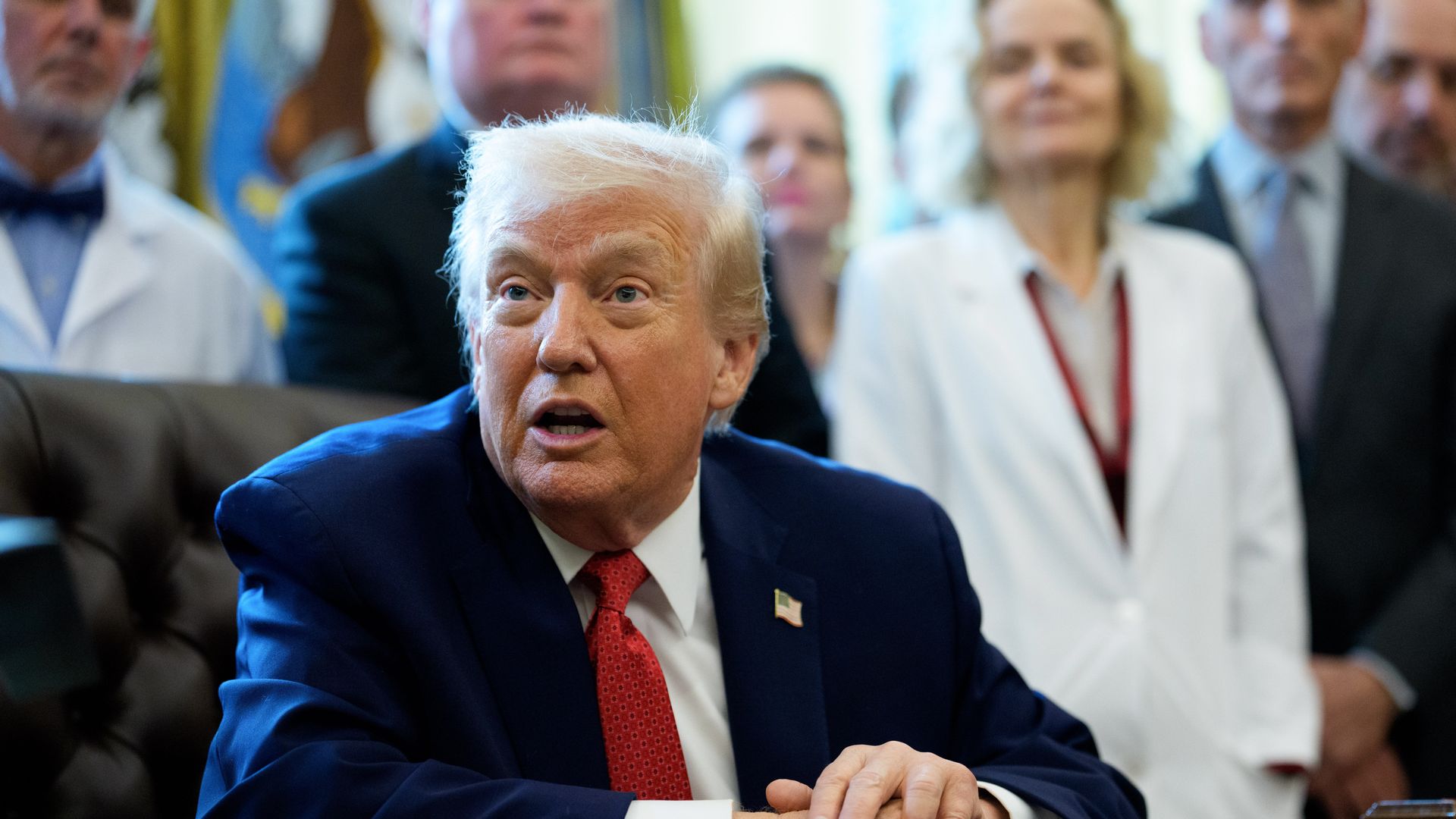 Donald Trump in a chair with his hands on a table. 