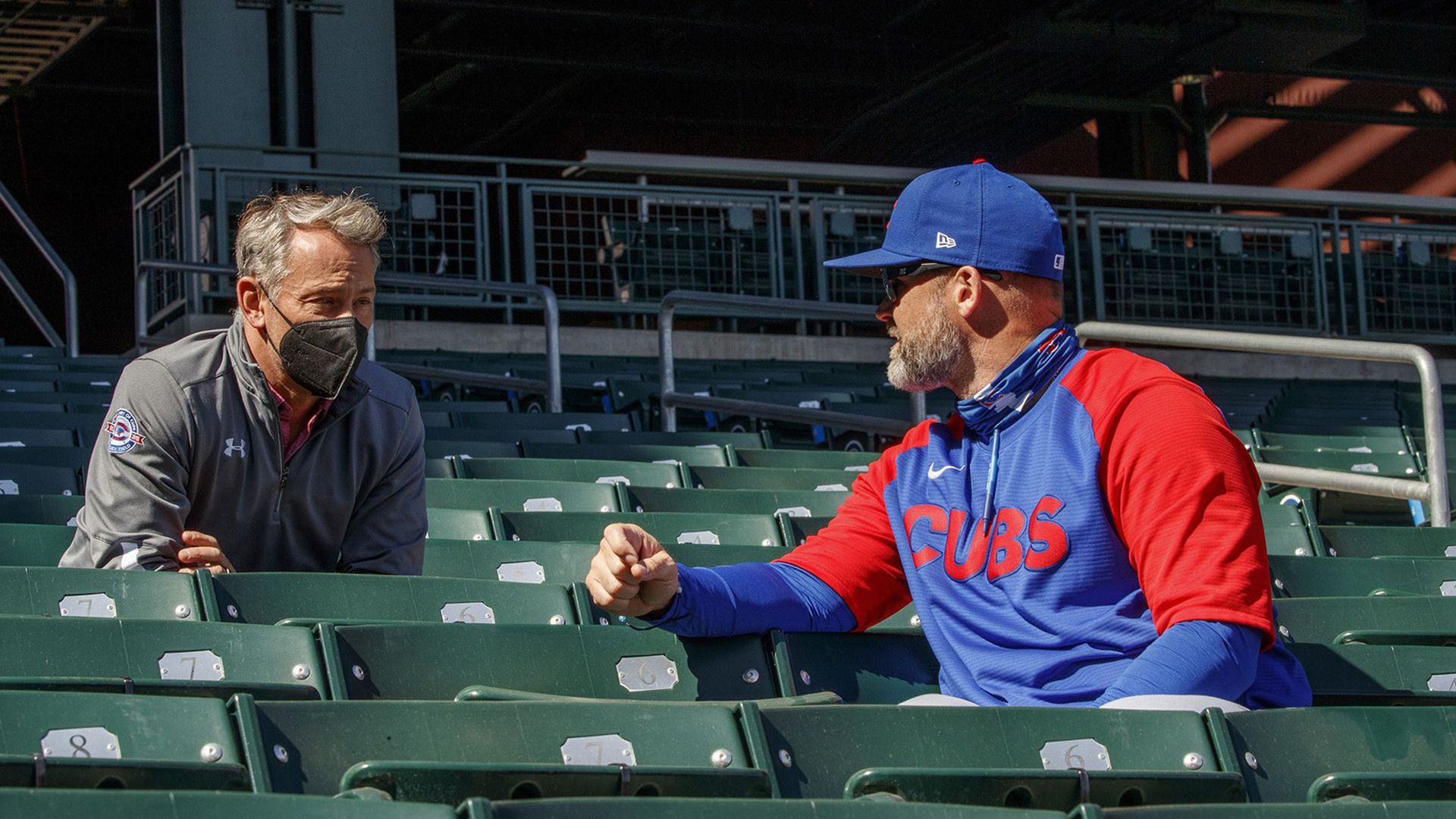 Two guys talking in a baseball stadium.