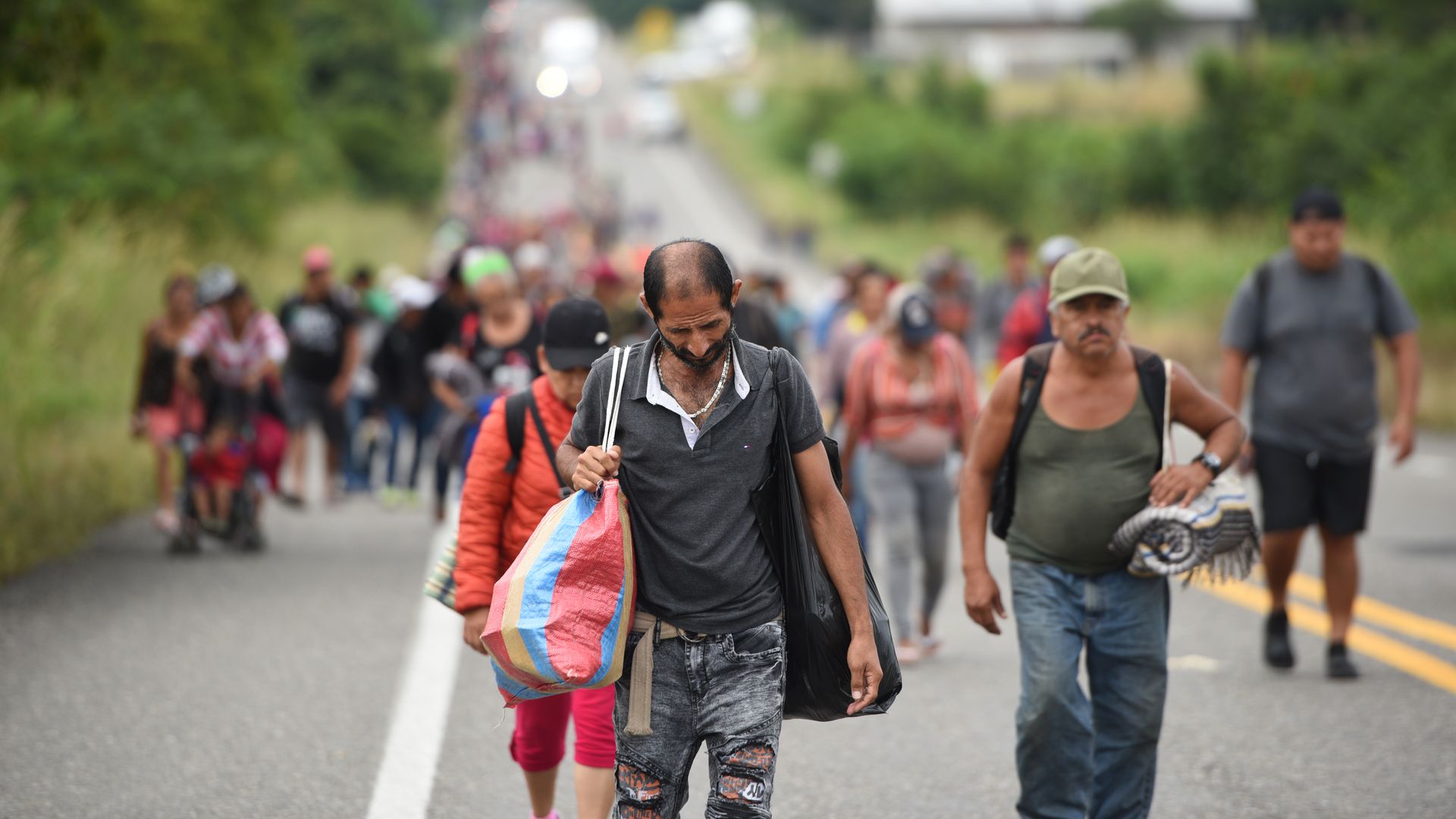 Migrants from Central America walk exhausted along a country road as they continue the march towards the US border