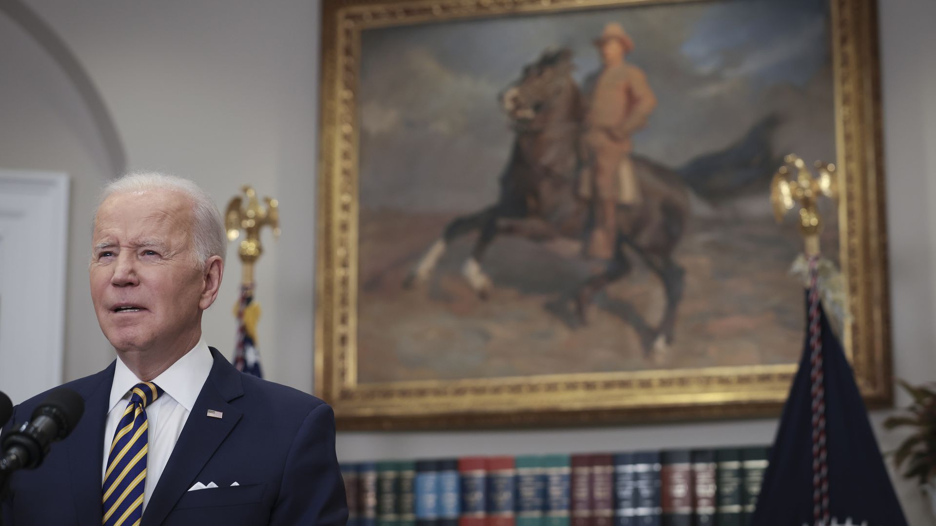 President Biden is seen speaking beneath a portrait of Teddy Roosevelt.