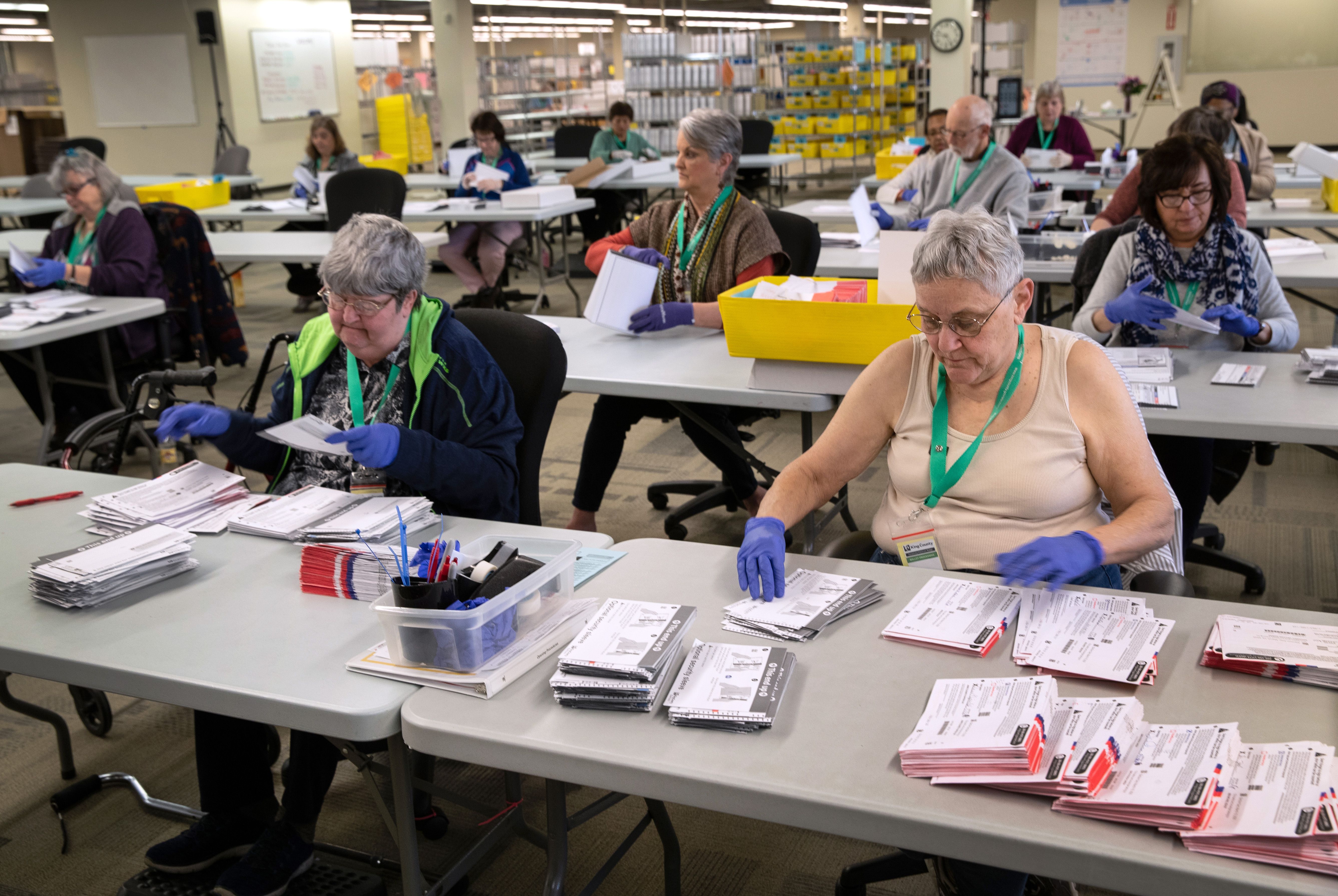 Election officials wear gloves while sorting through ballots