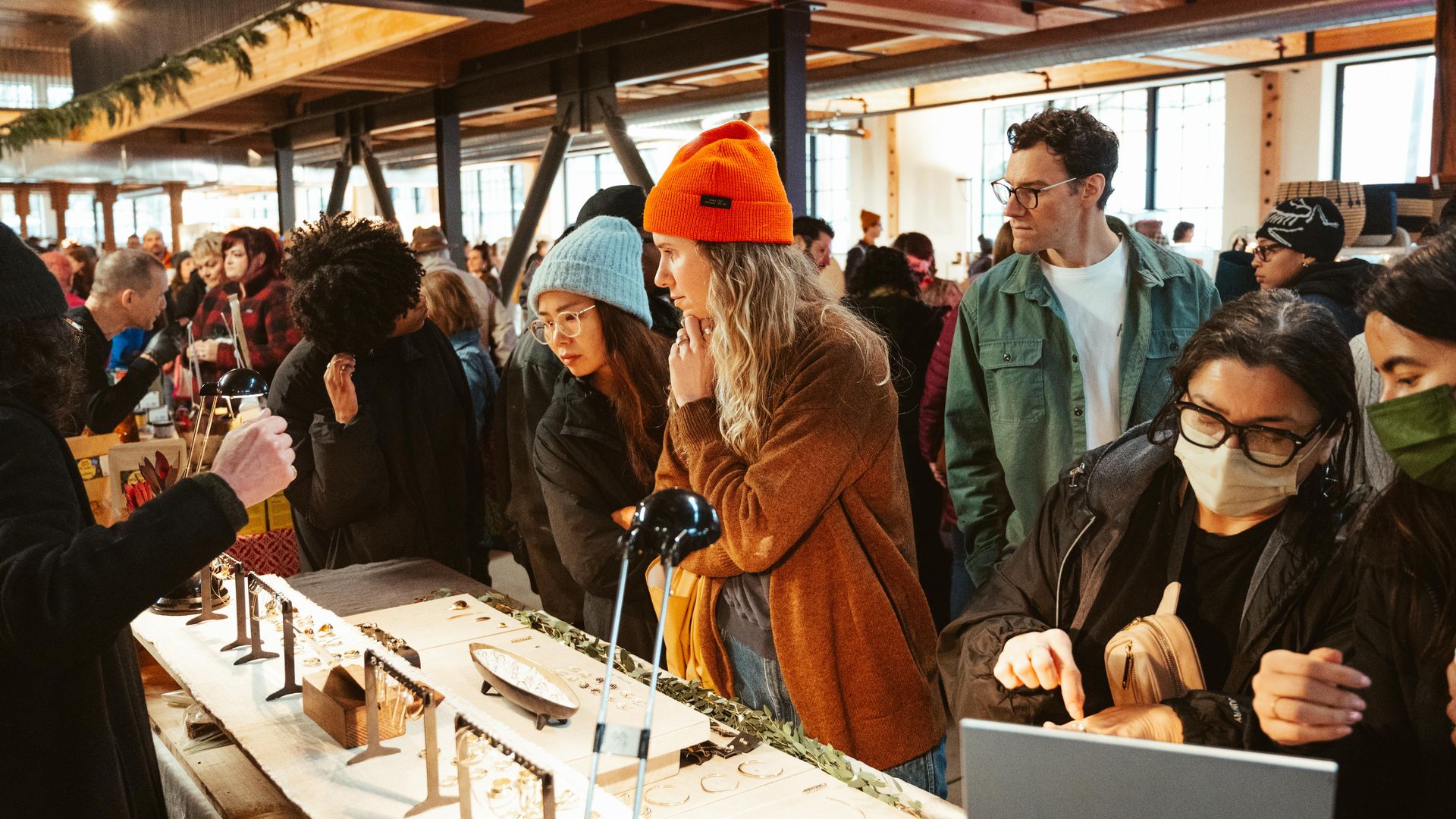 A photo showing people looking at a jewelry display at a crowded, holiday-themed market.
