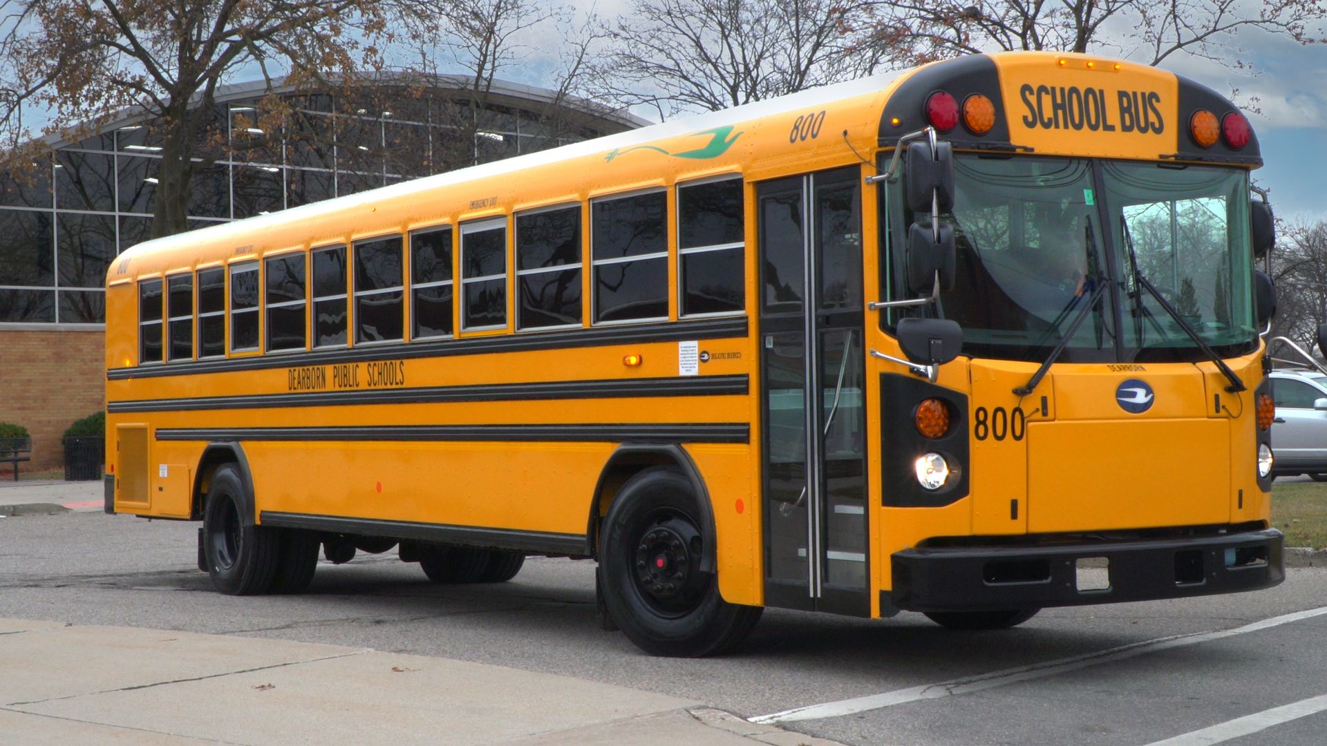 Photo of an electric school bus parked in front of a school 