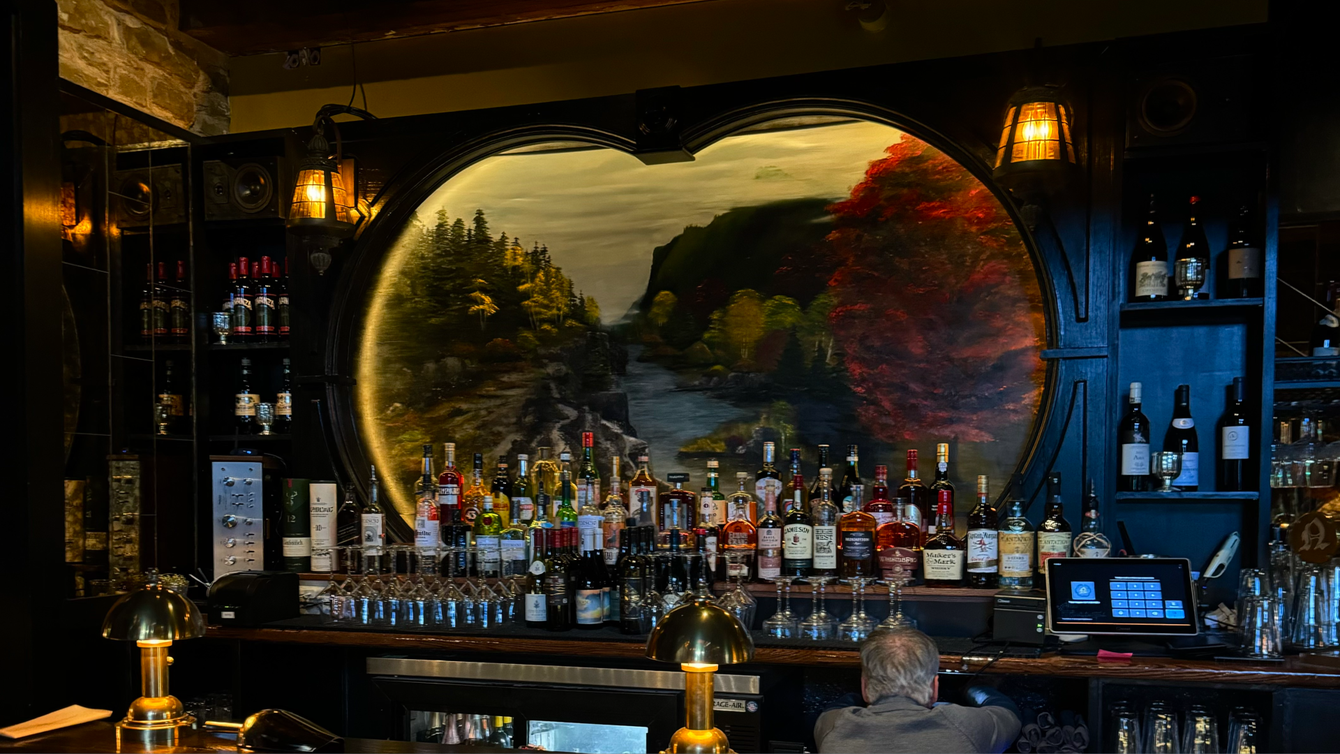 A bar with a handpainted mural of trees with red leaves.