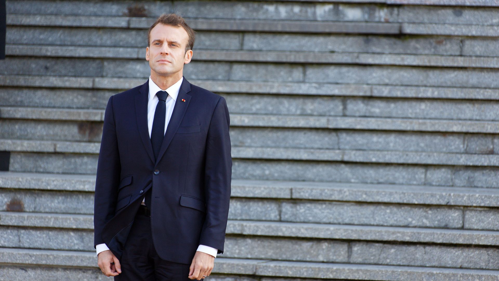 Emmanuel Macron standing on a set of steps outside. 