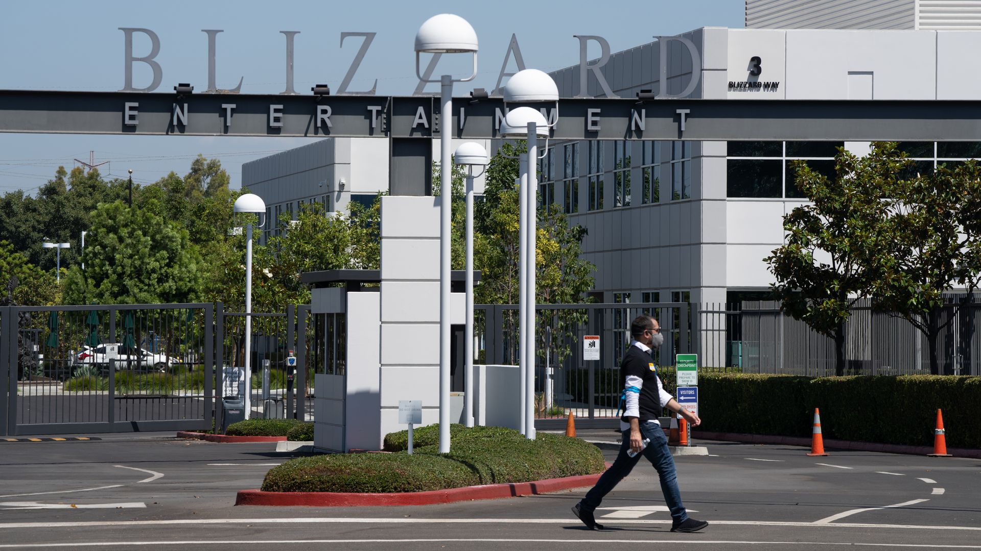 Photo of a person walking past an office gate that bears the word "Blizzard"