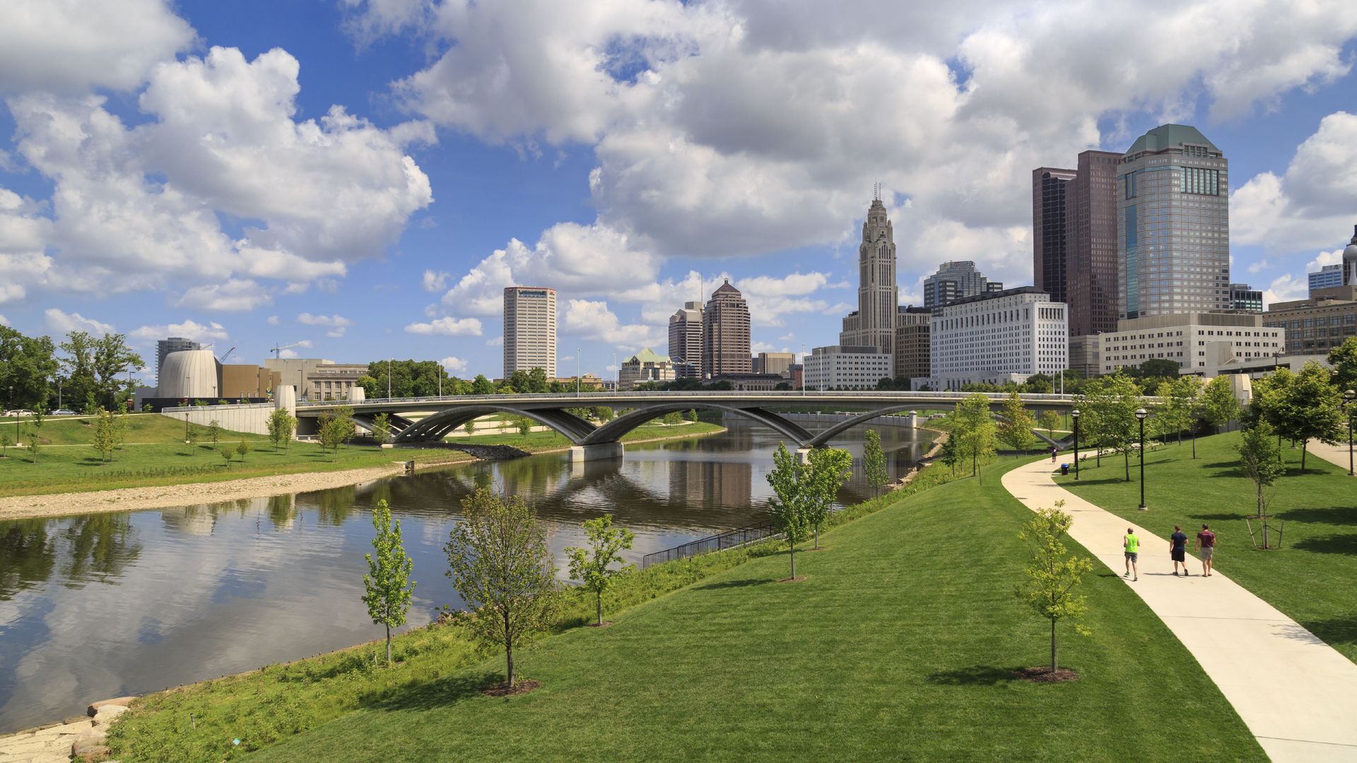 The Columbus, Ohio skyline, with a park, river, bridges and distant buildings.