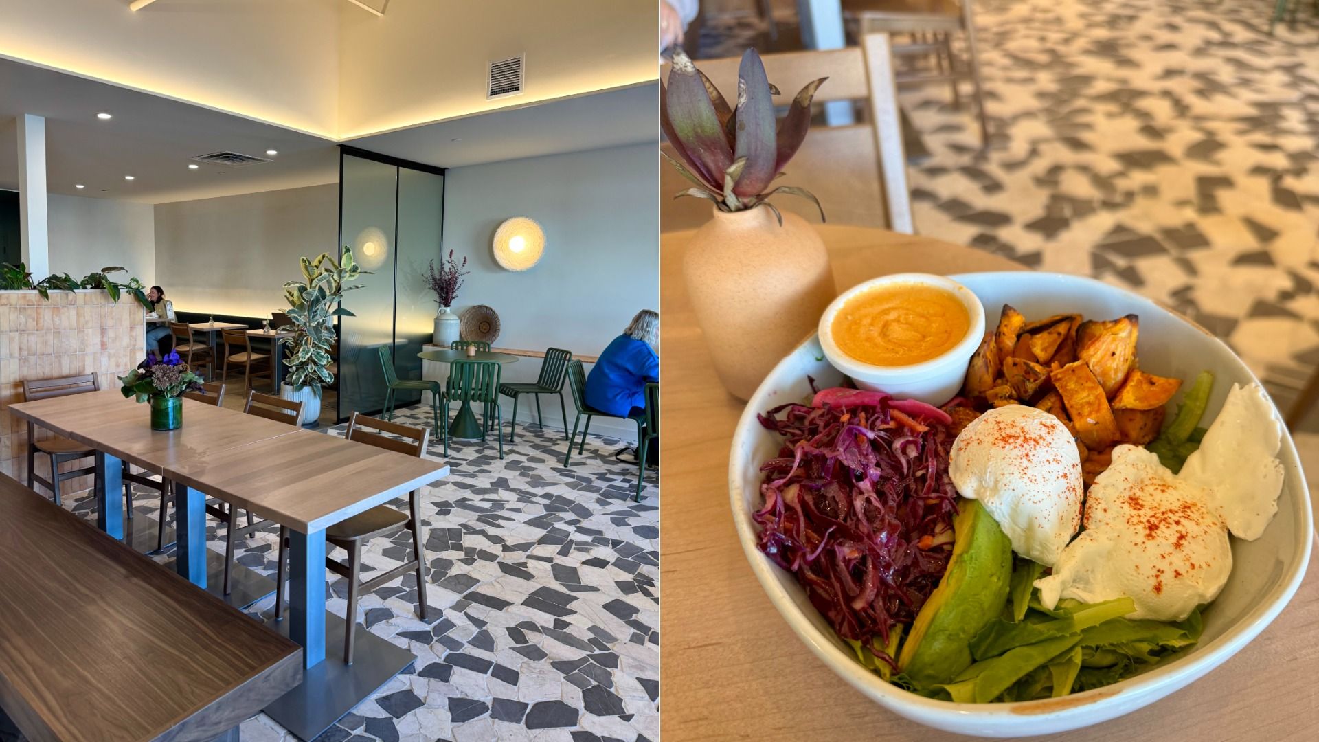 Bright cafe interior with wooden tables, green chairs, and mosaic tile floor. Bowl with poached eggs, avocado, roasted sweet potatoes, shredded red cabbage, and a cup of orange sauce on a wooden table.