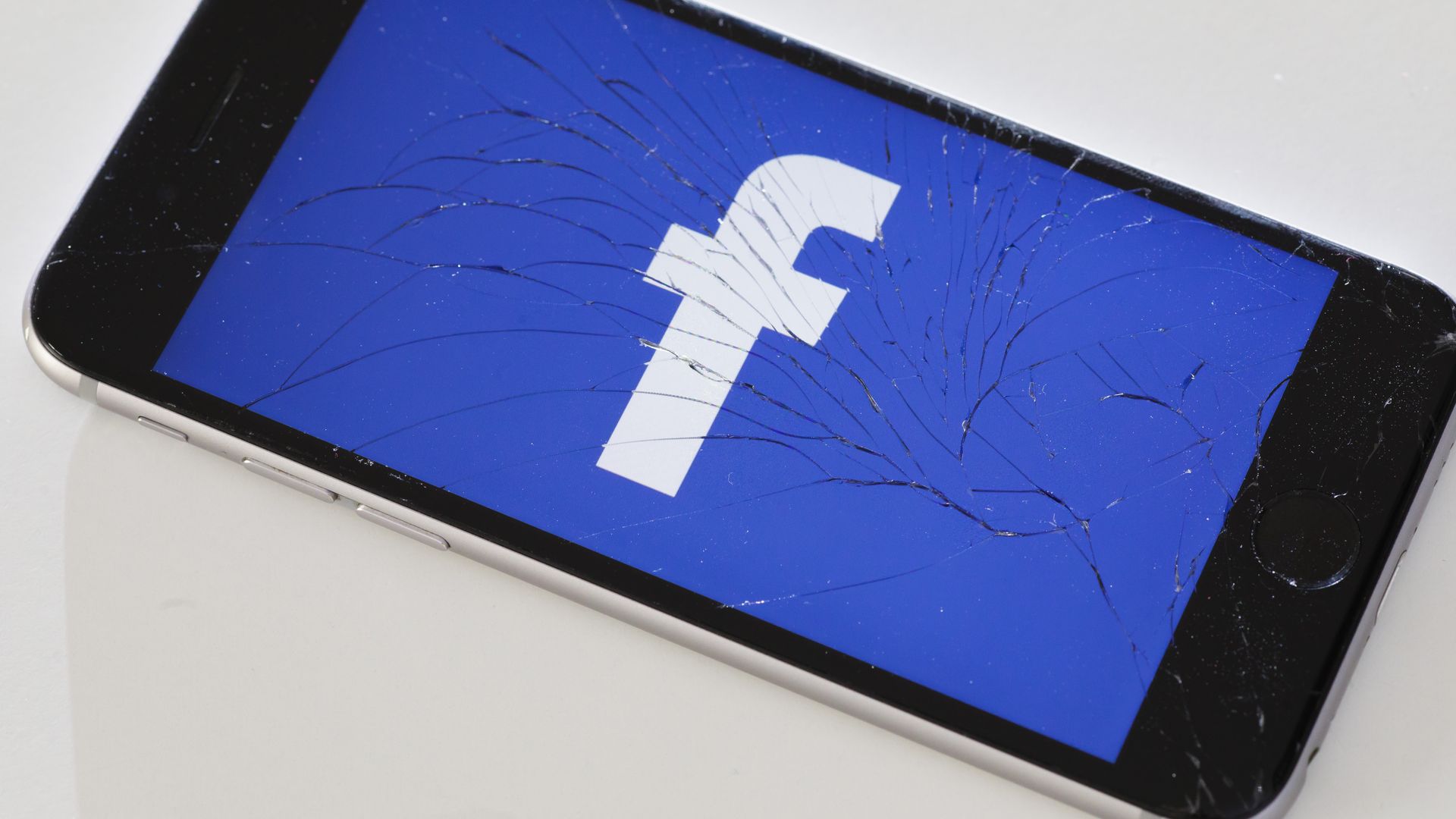 Facebook logo on a cracked smartphone screen
