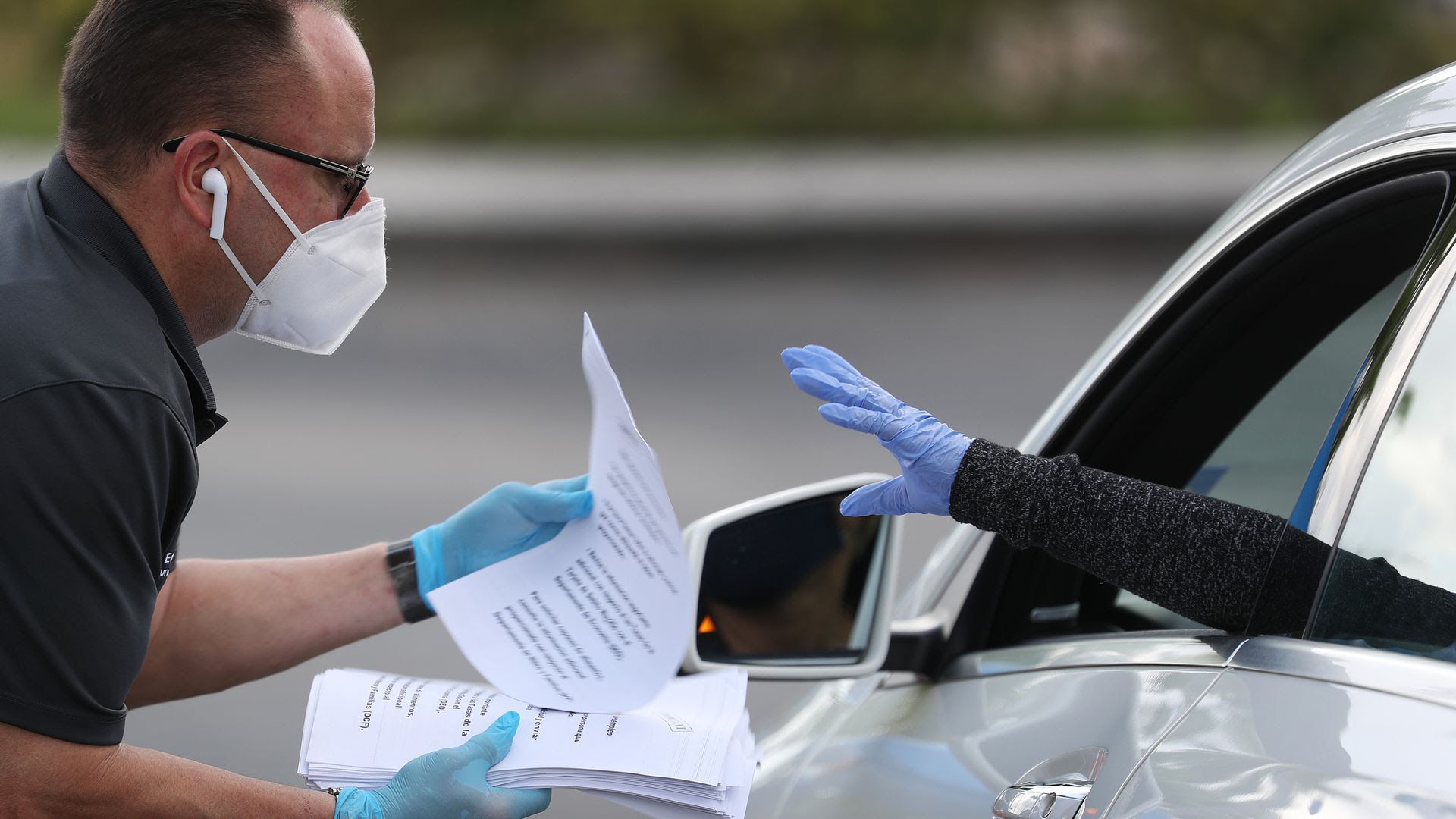 Eddie Rodriguez hands out unemployment applications to people in their vehicles