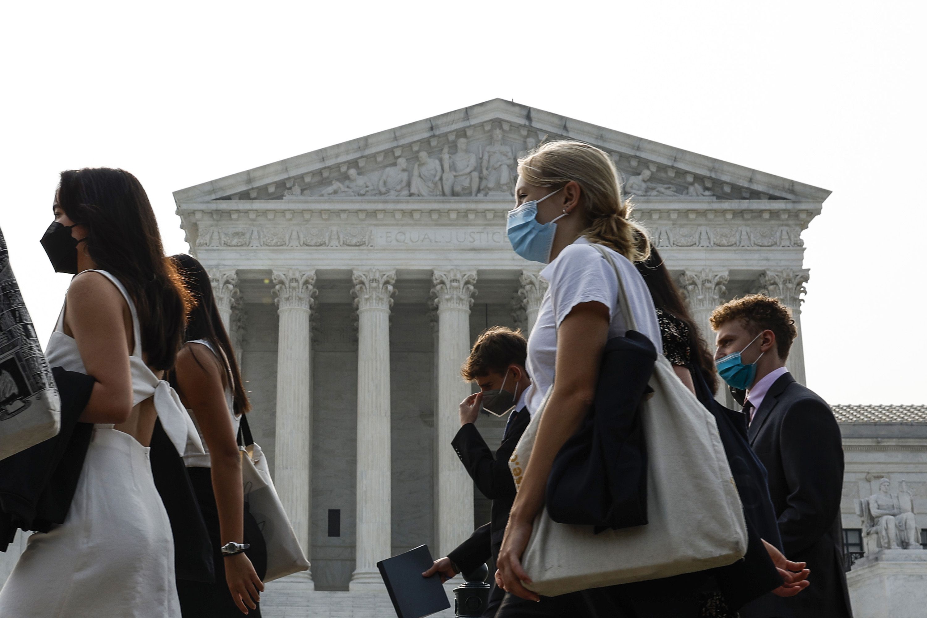 A group of people wear face masks to protect against air pollution as they walk past the U.S. Supreme Court Building on June 29, 2023 in Washington, DC. The Washington DC region is under a "Code Red" air quality alert today due to smoke from Canadian wildfires. 