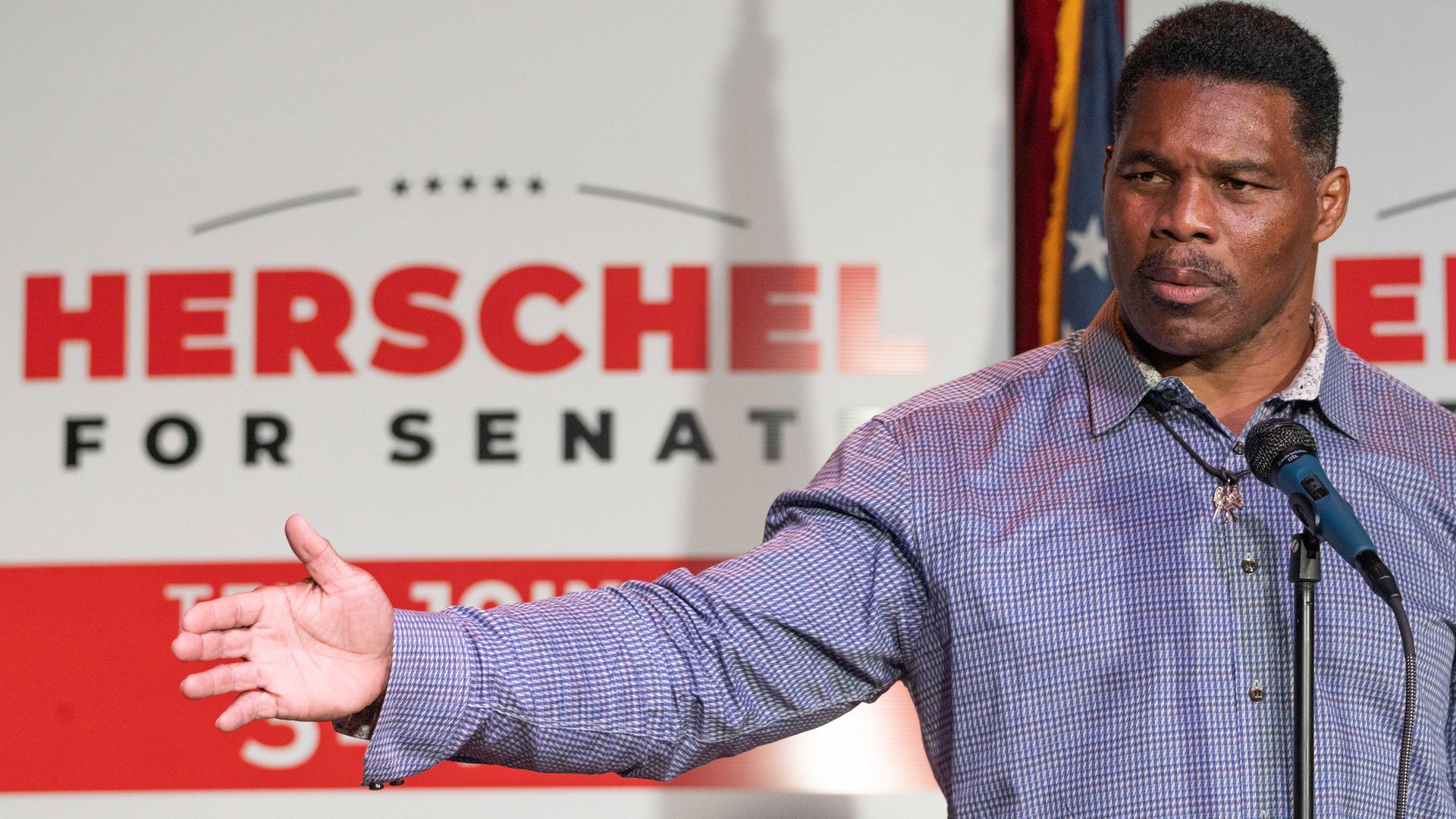 Herschel Walker in front of a sign that says his first name