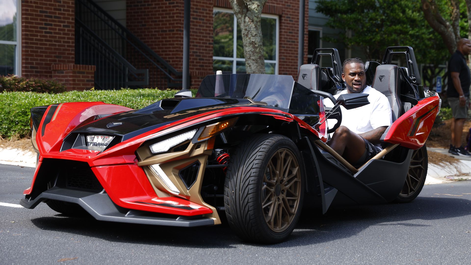 A photo of Atlanta Falcons running back Cordarrelle Patterson arrives at the team's NFL football camp in an open-air car with two large wheels in front and one in back