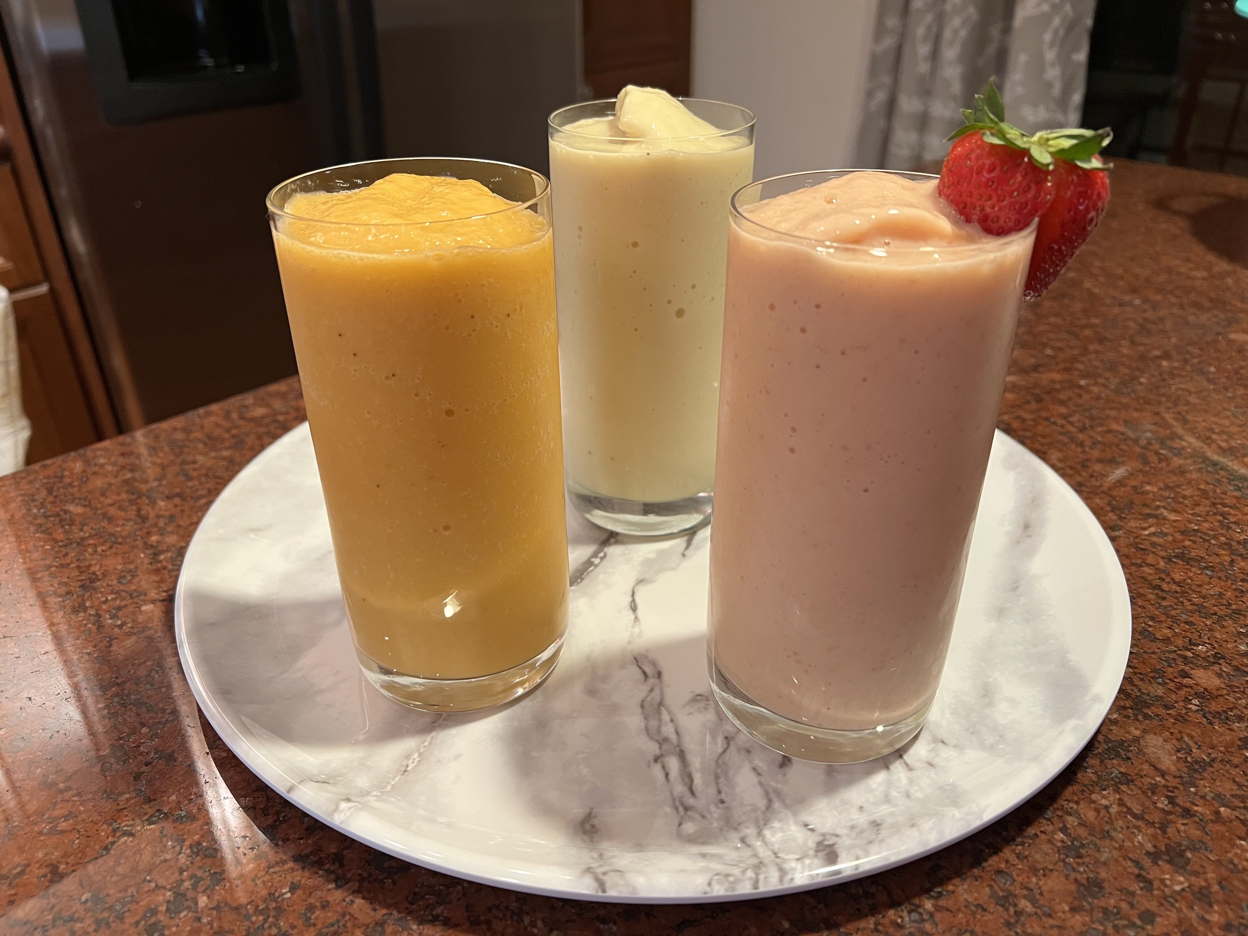 Photo of three smoothies in glasswear on a plate.
