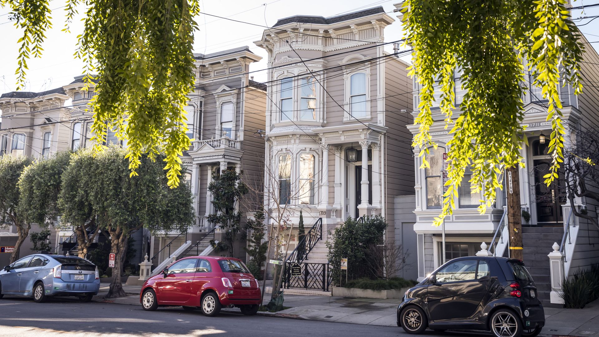 A Victorian home with a red car parked out front