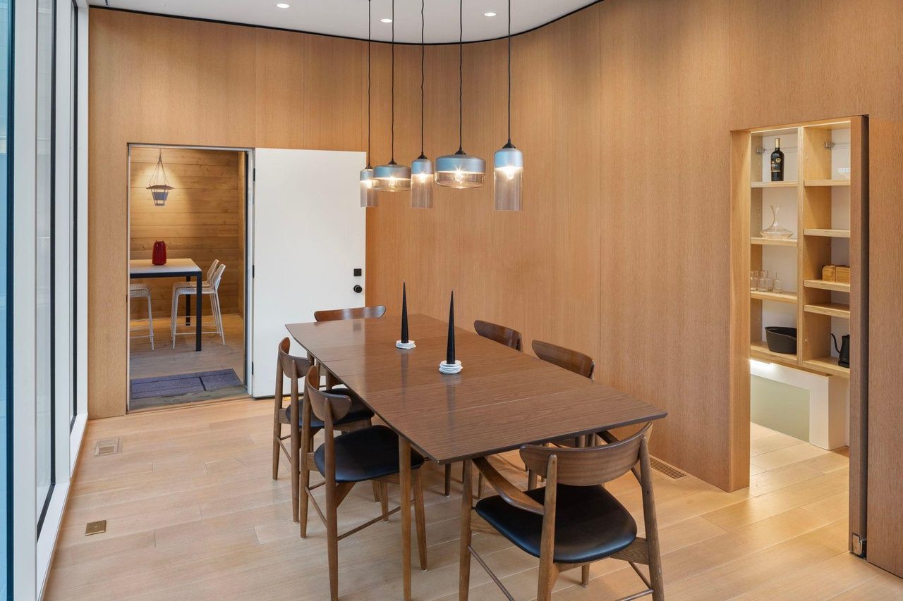 A dining room with a wood table and wood walls.