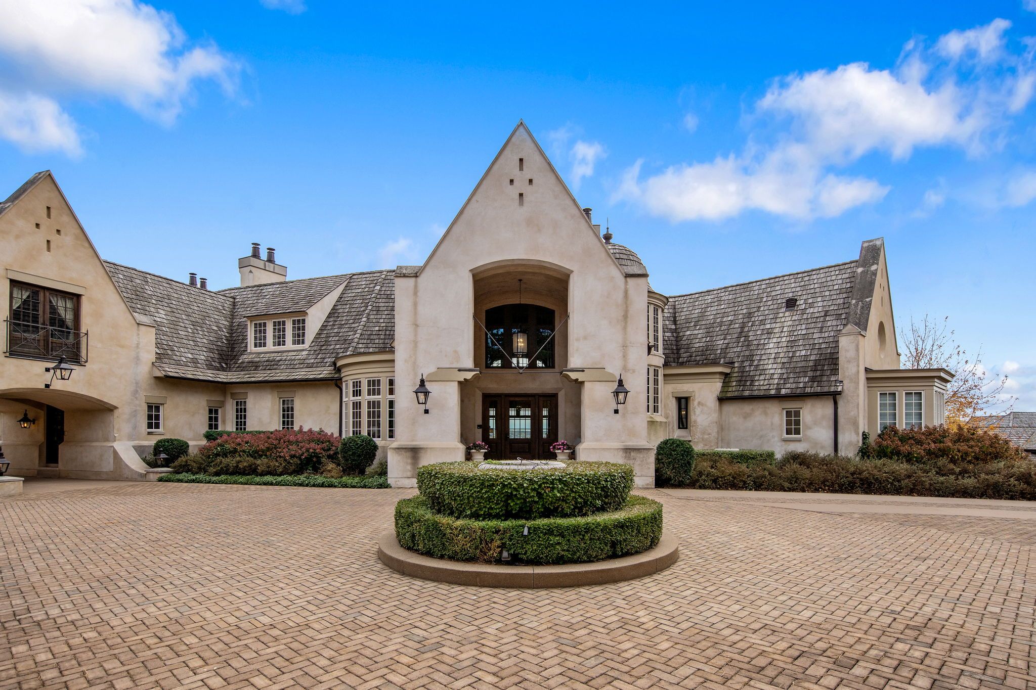 The exterior of a white house with a brick driveway.
