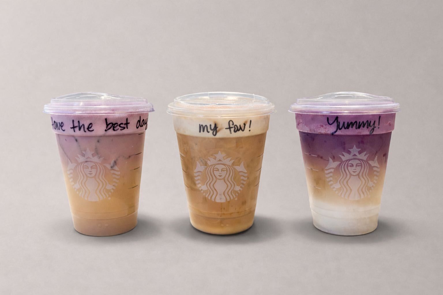 Three Starbucks iced drinks with handwritten messages on lids: "Have the best day," "my fav!", and "Yummy!", featuring purple, beige, and white layered colors.