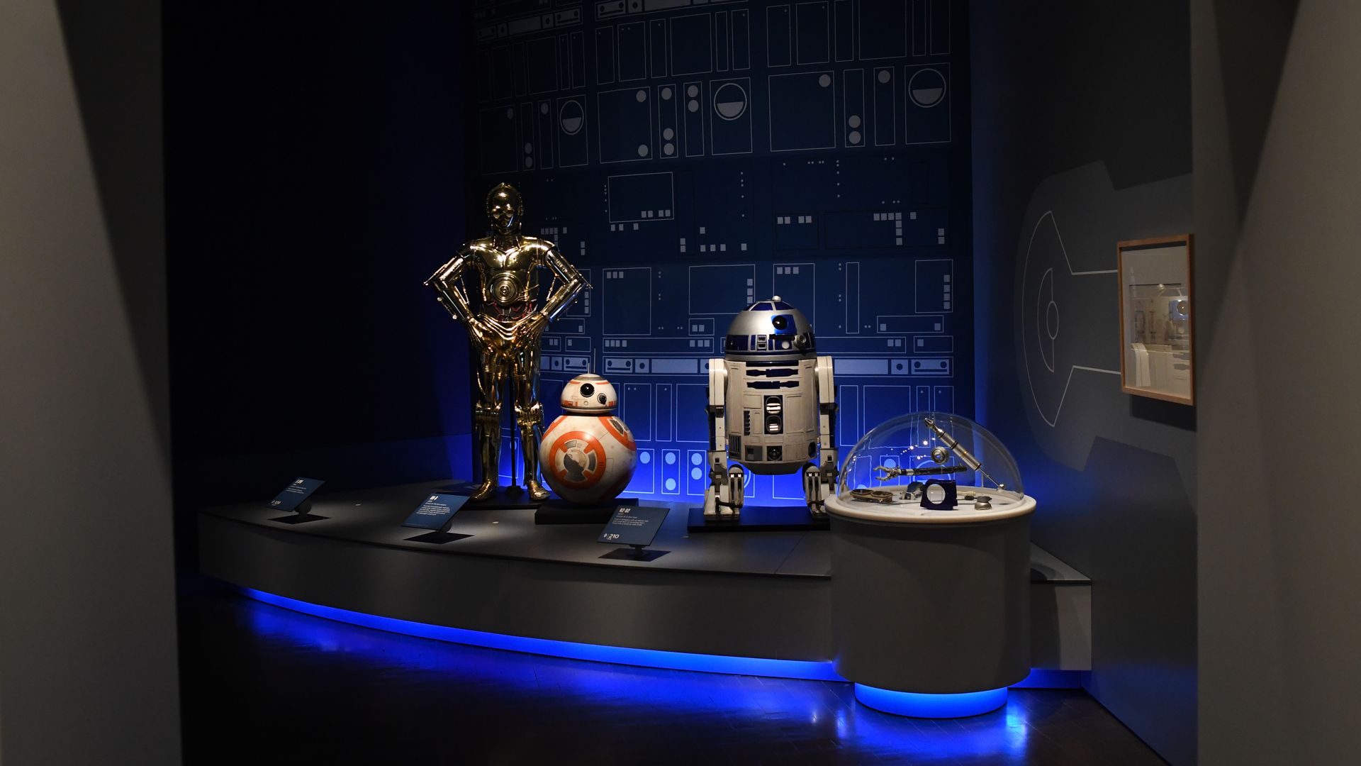 Star Wars droid costumes, including R2-D2 and C-3PO, on display at a previous Star Wars exhibit at the Denver Art Museum.