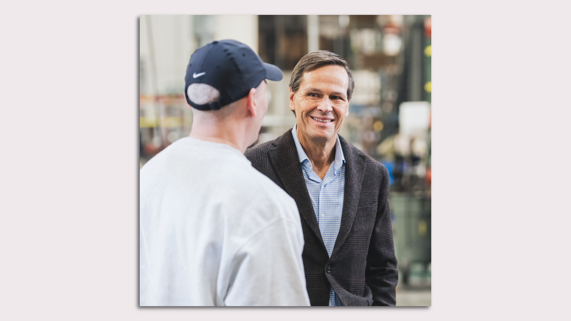 A man in a suit talking to a man in a hat
