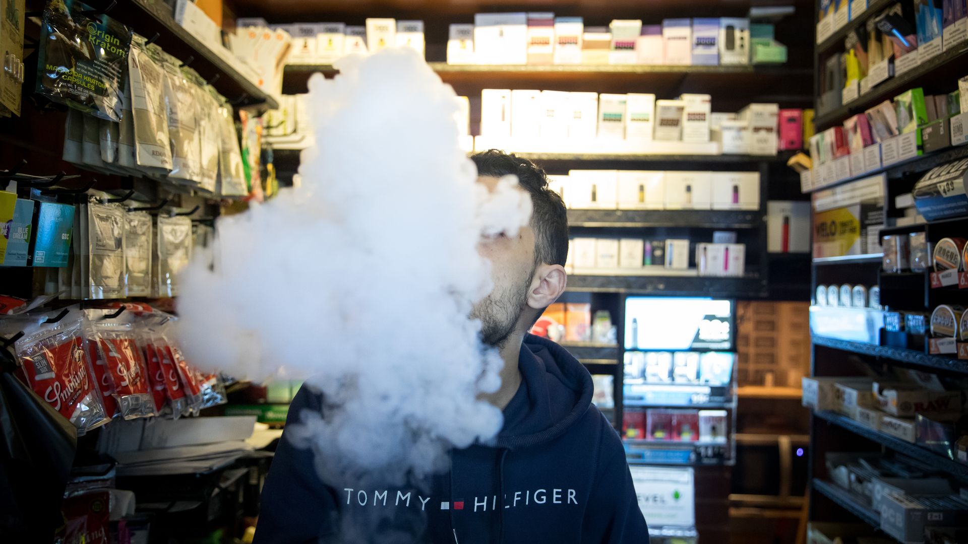 A photo of a person exhaling vapor while using an electronic cigarette device at a smoke shop