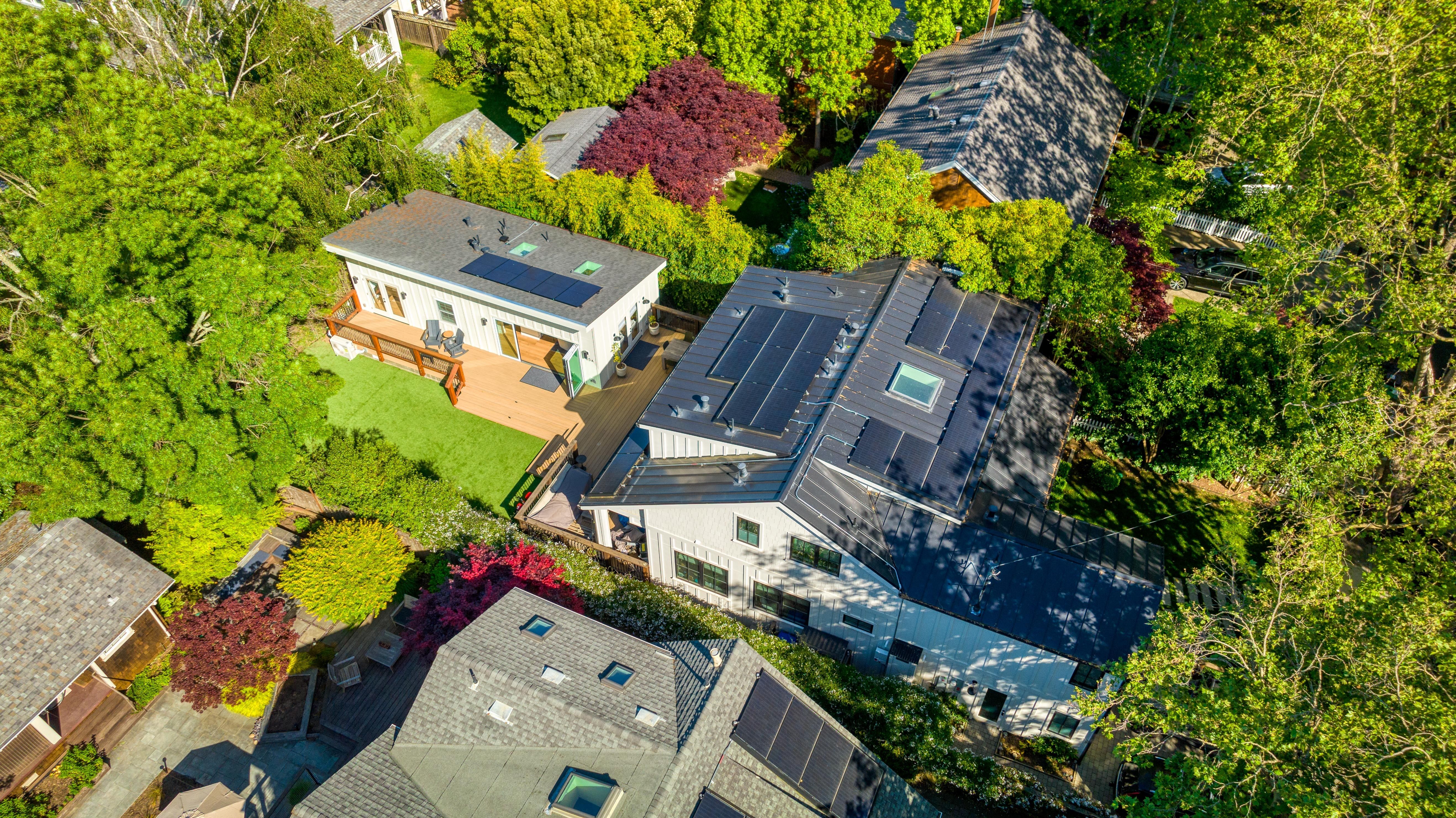 A backyard accessory dwelling unit is shown from above, with a larger house to the right.