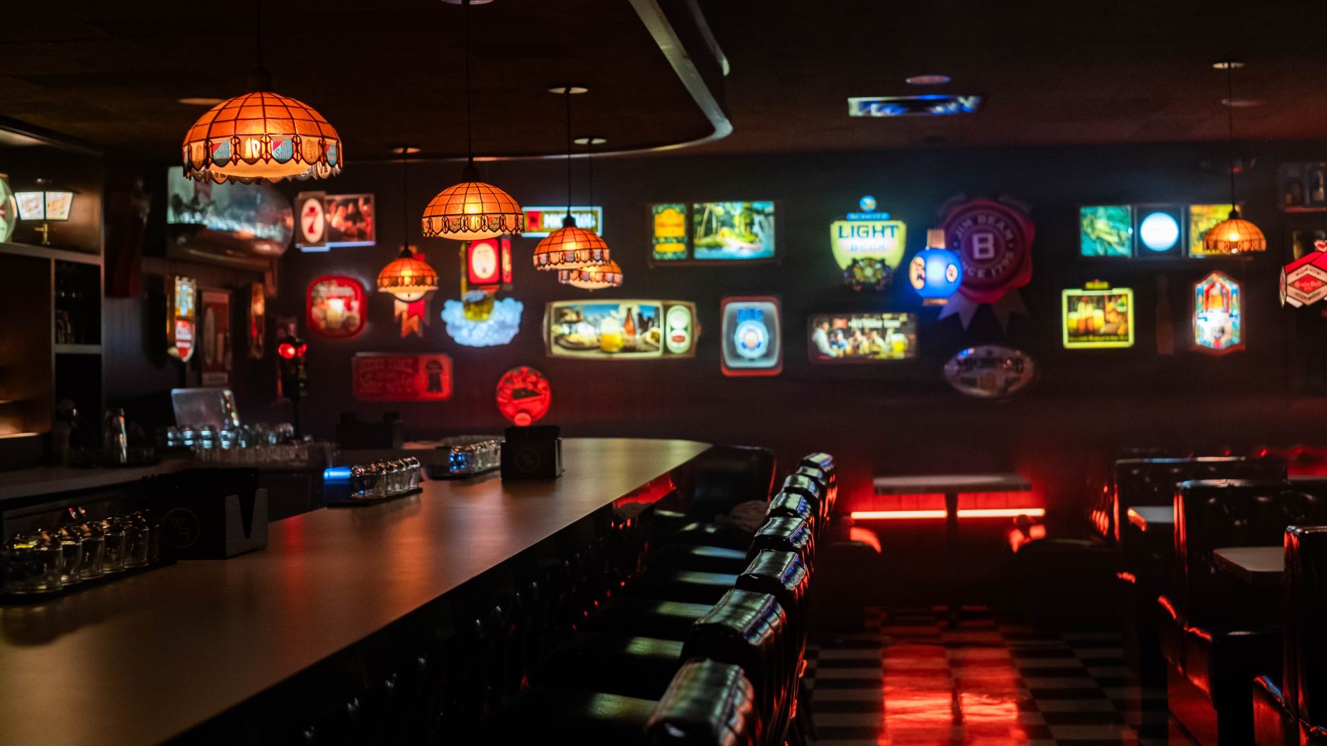 A bar lit by neon and classic chandelier lighting.